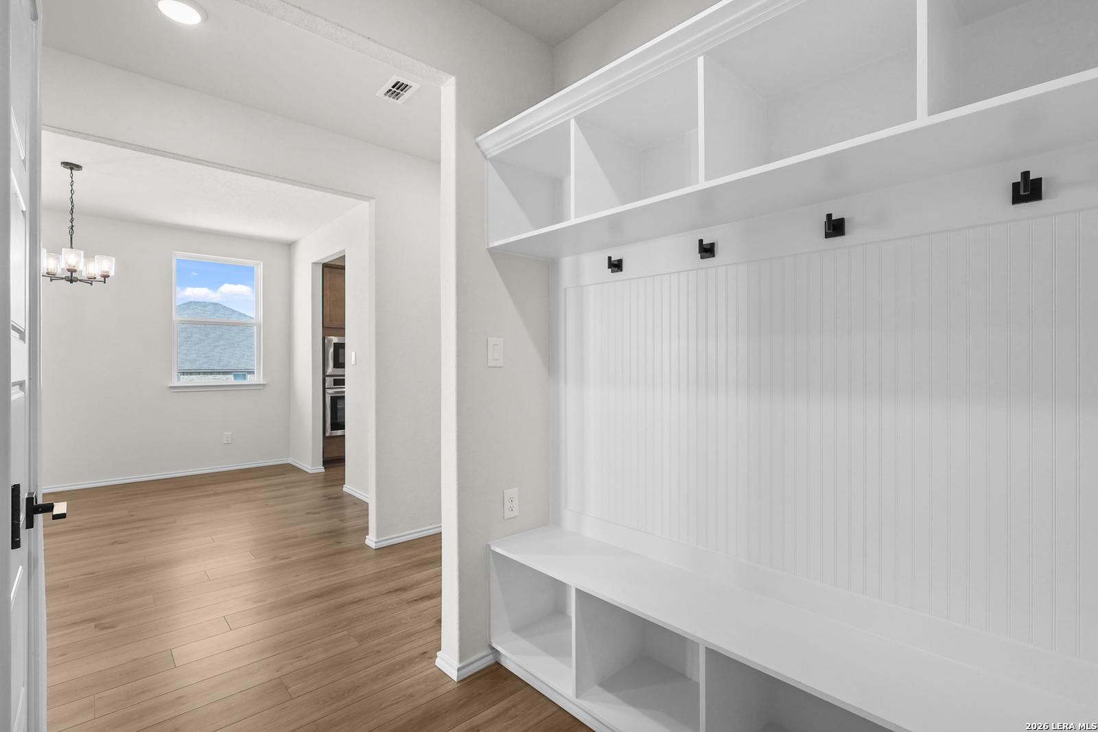 Mudroom with built-in bench, cubbies, coat hooks and wood-look flooring in Davidson Homes Glenwood E plan, Comanche Ridge, San Antonio
