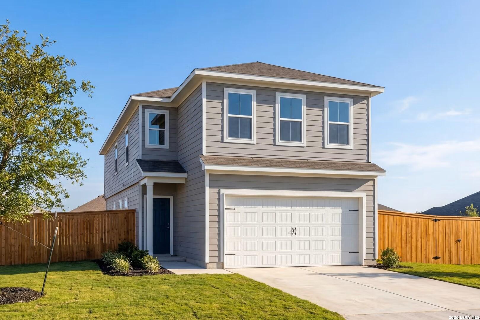 Two-story gray home with white two-car garage, blue front door, landscaped yard, and wooden fence in Cedar Heights, San Antonio, Texas – Davidson Homes The Gillian A