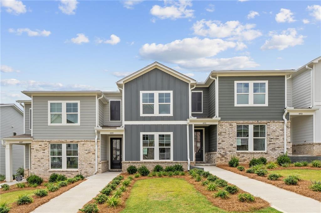 Modern gray townhomes with brick accents, garages, and landscaped front yards in Stegall Village, Emerson, Georgia by Davidson Homes