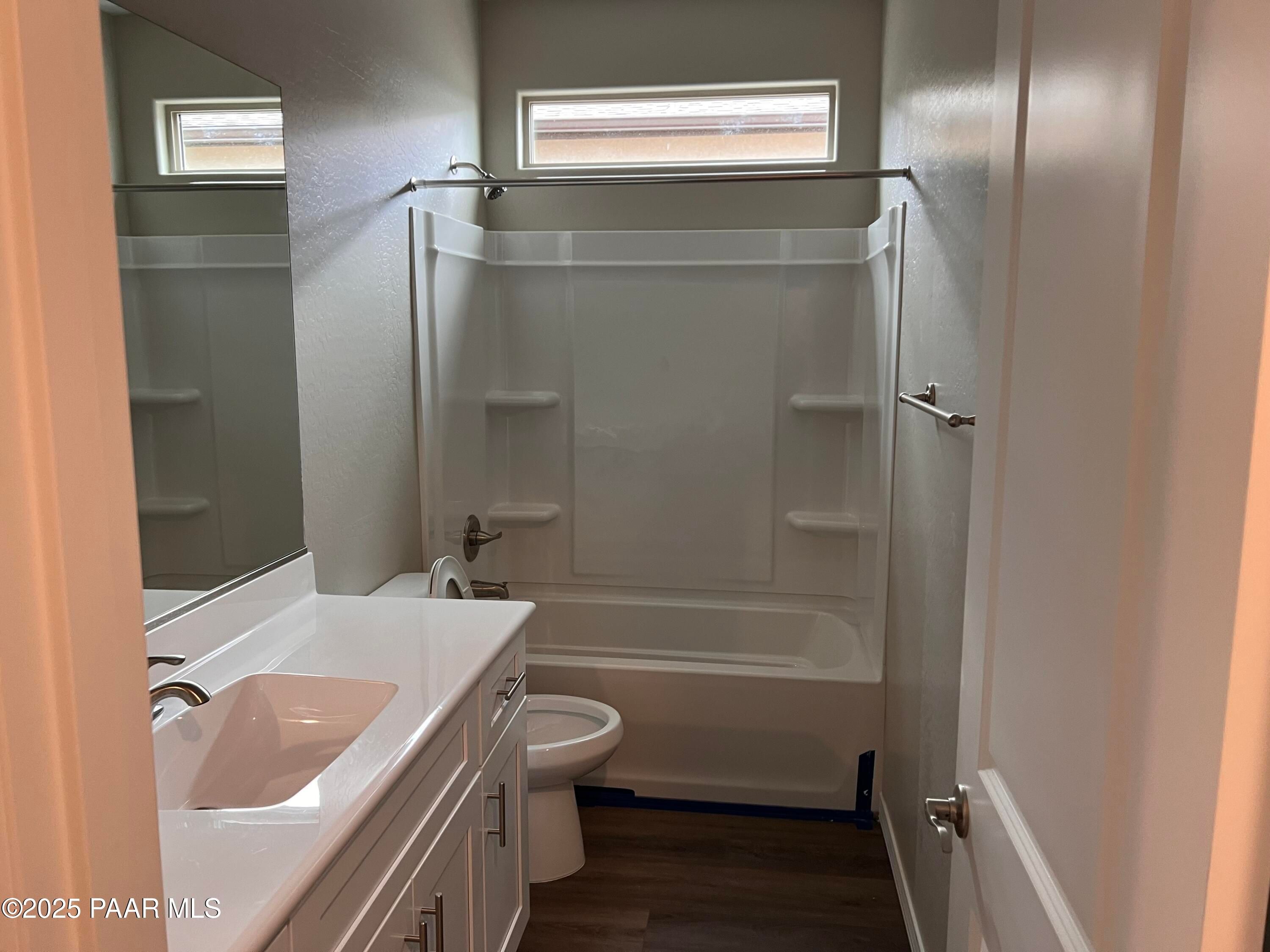 Modern bathroom with white vanity, bathtub-shower combo, toilet, and clerestory window in Davidson Homes The Harmony A, Prescott Valley, Arizona