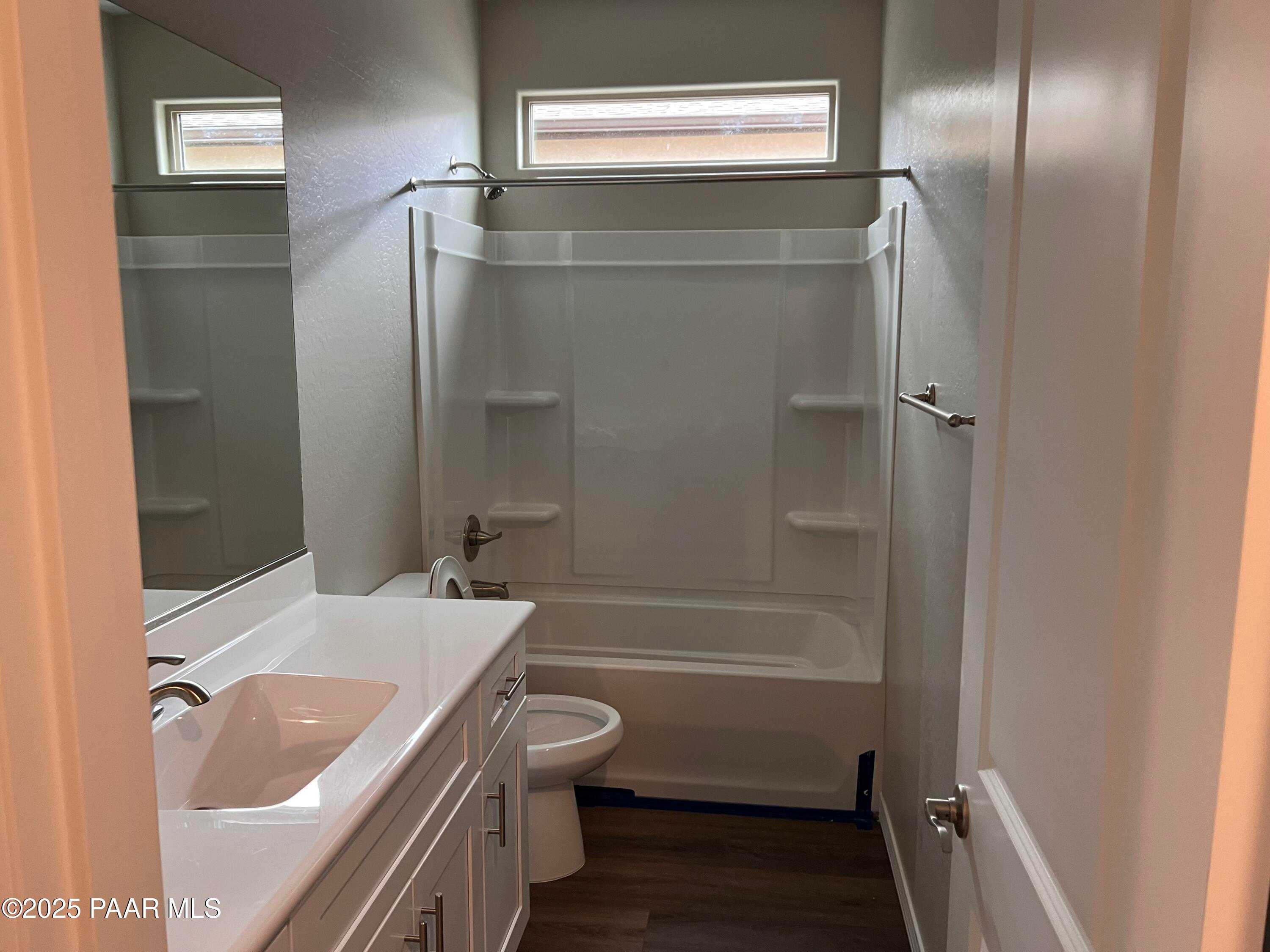 Modern bathroom with white vanity, bathtub-shower combo, toilet, and clerestory window in Davidson Homes The Harmony A, Prescott Valley, Arizona