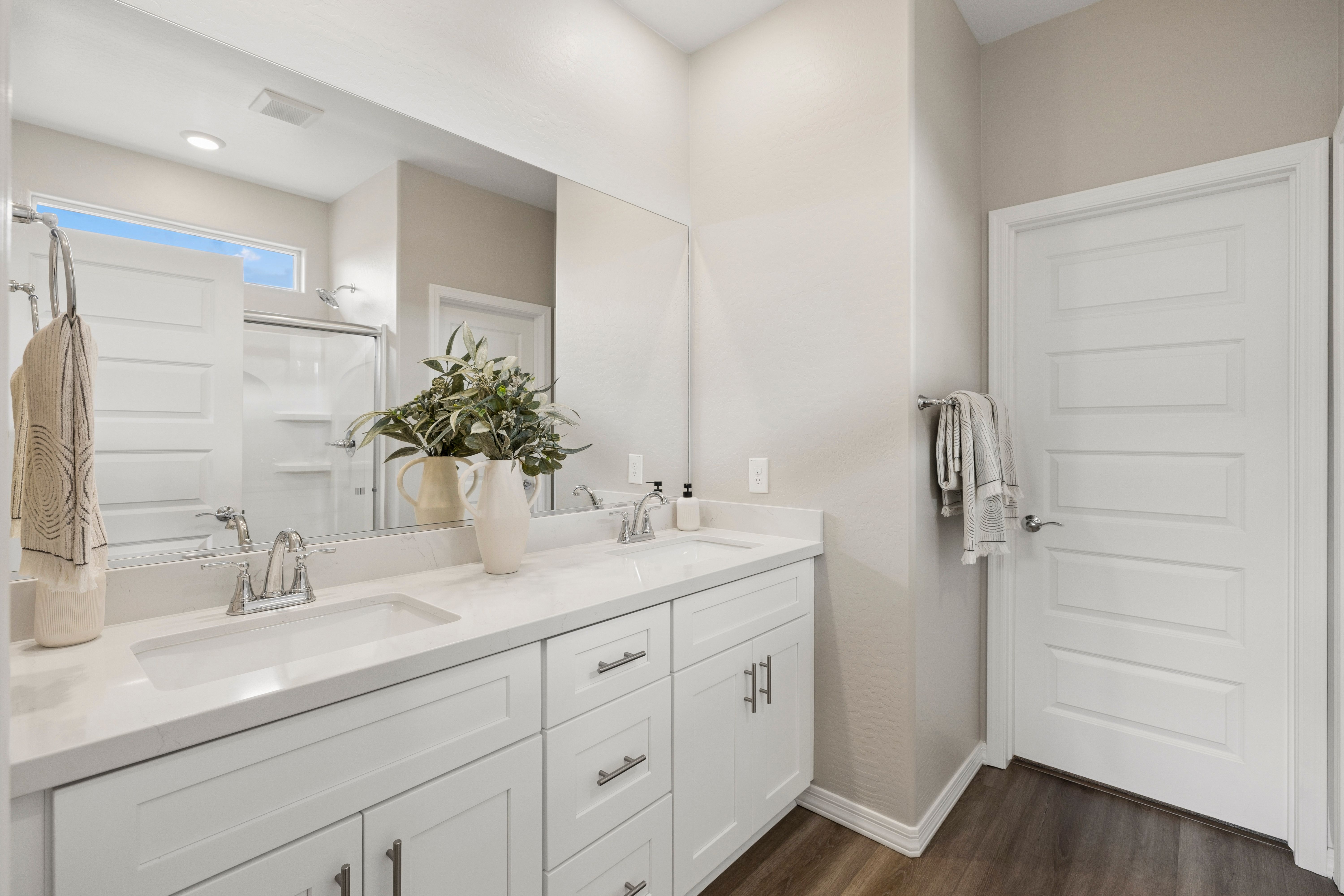 Modern primary bathroom at South Ranch Destination Collection in Prescott AZ with double white vanity quartz counters and glass shower