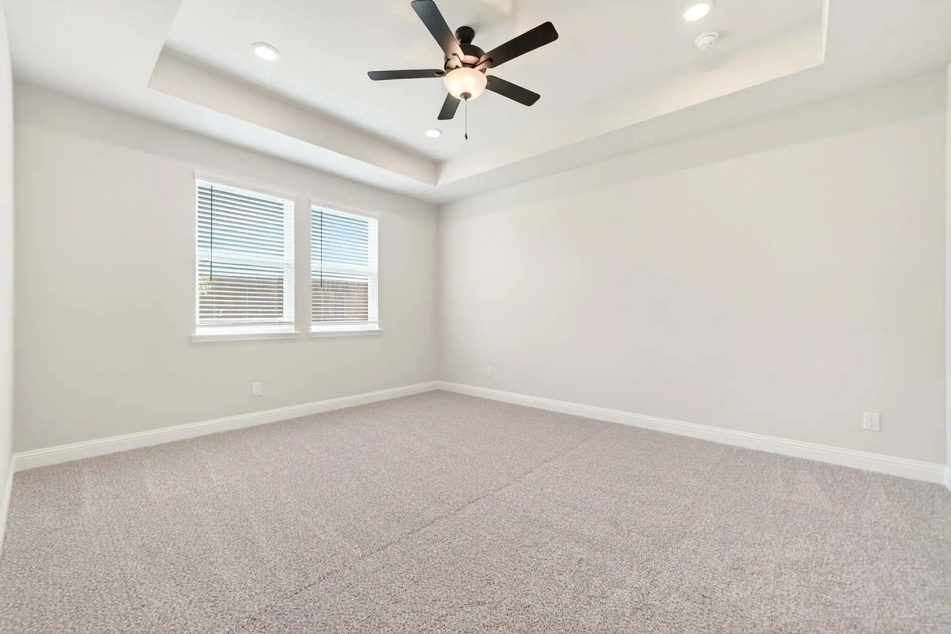Spacious bedroom with tray ceiling and ceiling fan in The Holly C floor plan by Davidson Homes in Heartland, Texas.