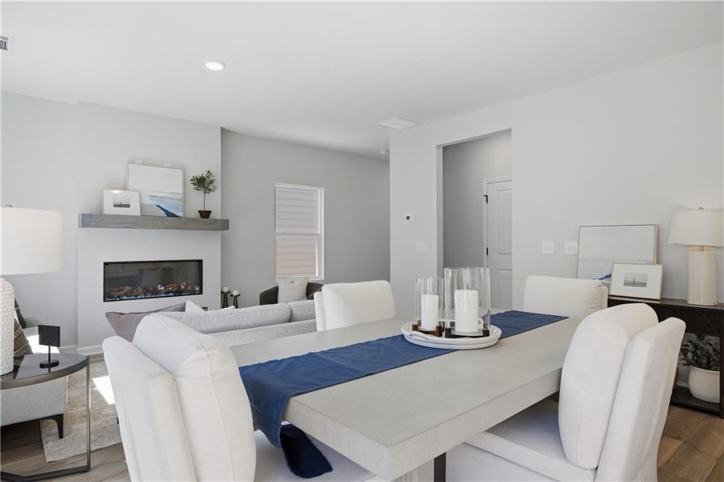 Bright dining area with linear fireplace and white upholstered chairs in Davidson Homes' Hartwell C plan, The Bluffs, Canton, GA