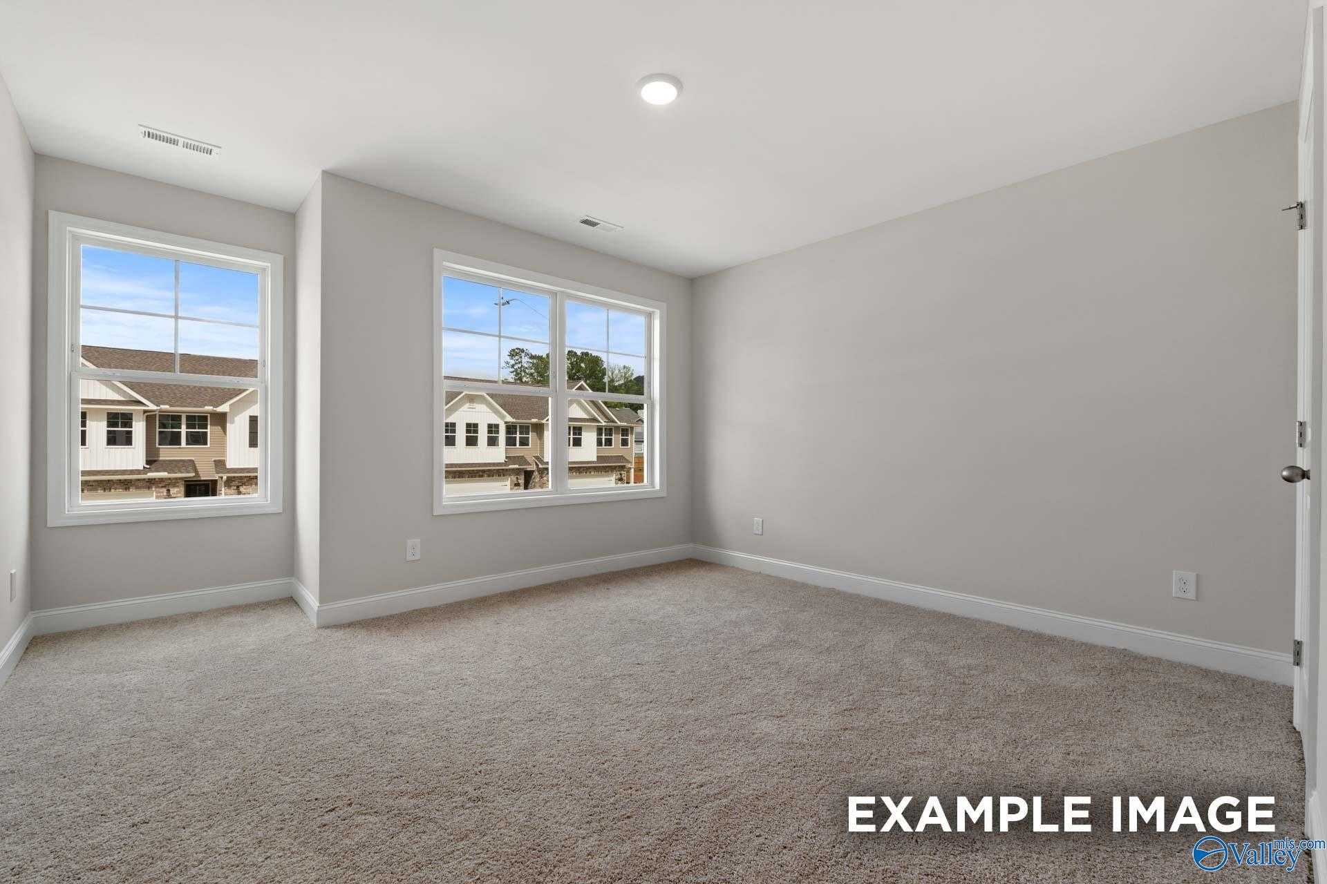 Bright secondary bedroom with large windows, plush beige carpet, and neighborhood views in Davidson Homes The Camden, Huntsville, AL