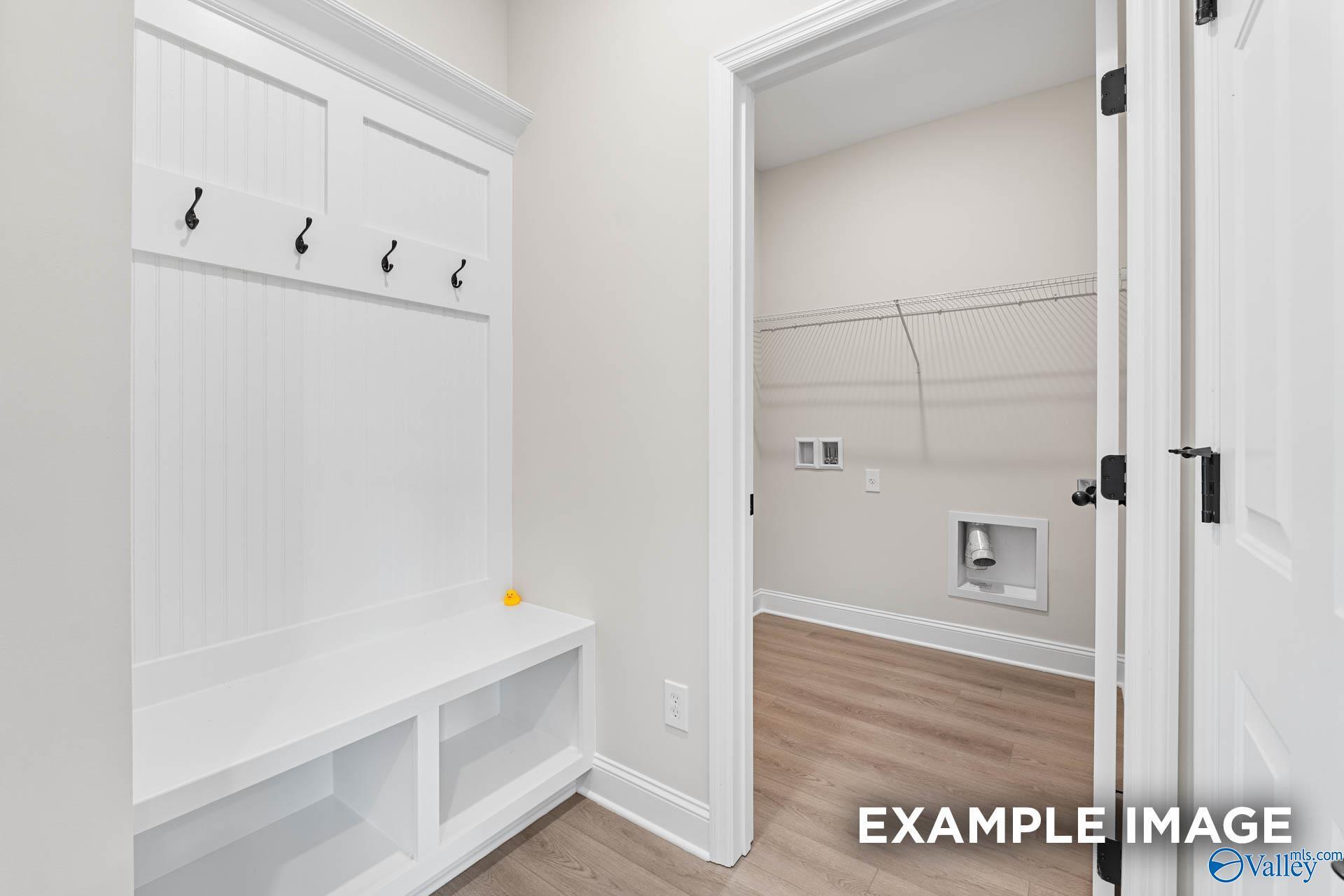 Mudroom with built-in bench and coat hooks leading to laundry room in The Franklin B floor plan at Creekside in Harvest.