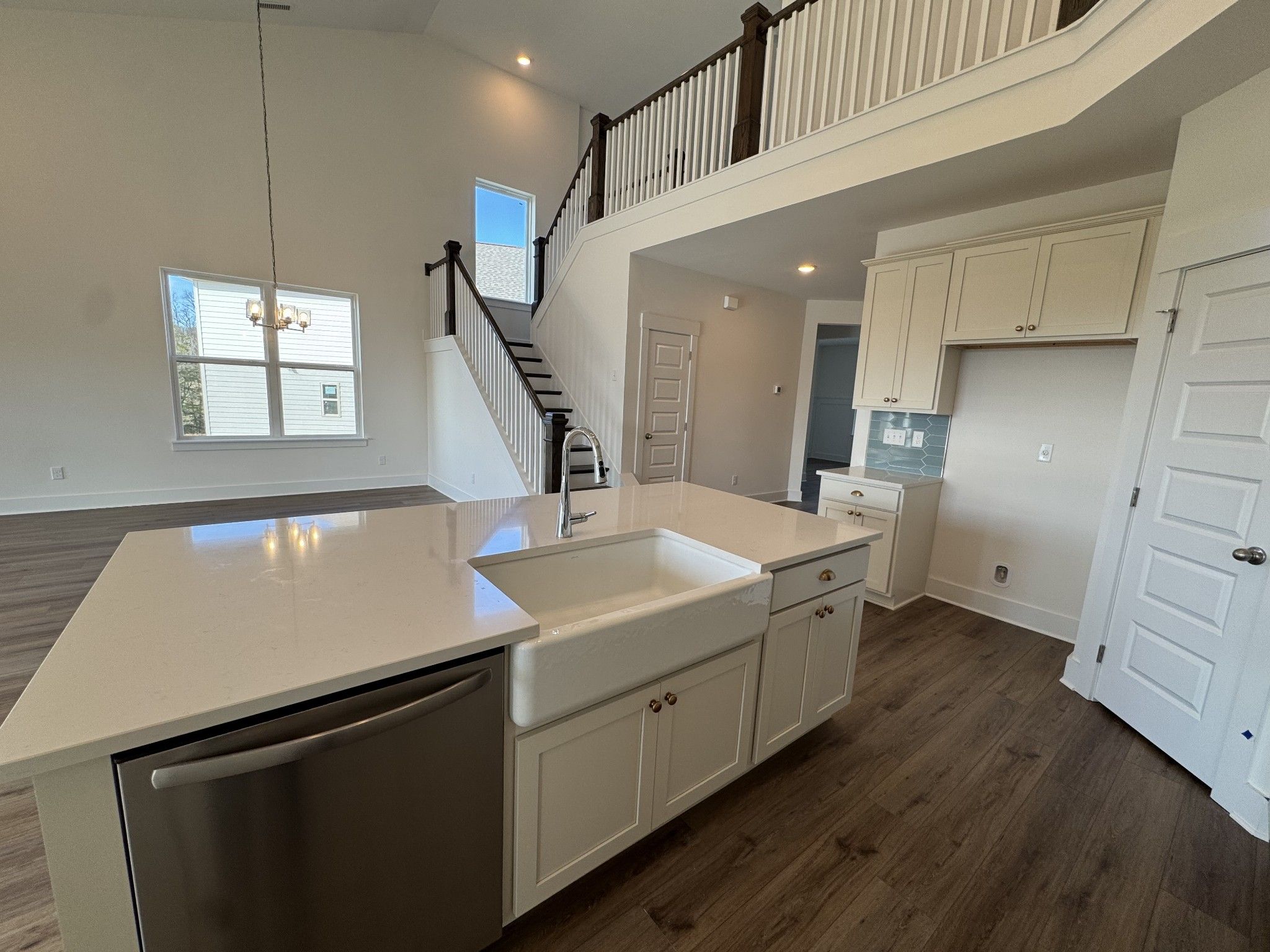 Open-concept kitchen with white quartz island, farmhouse sink, and staircase overlook in The Ridgeport home, Gallatin, TN