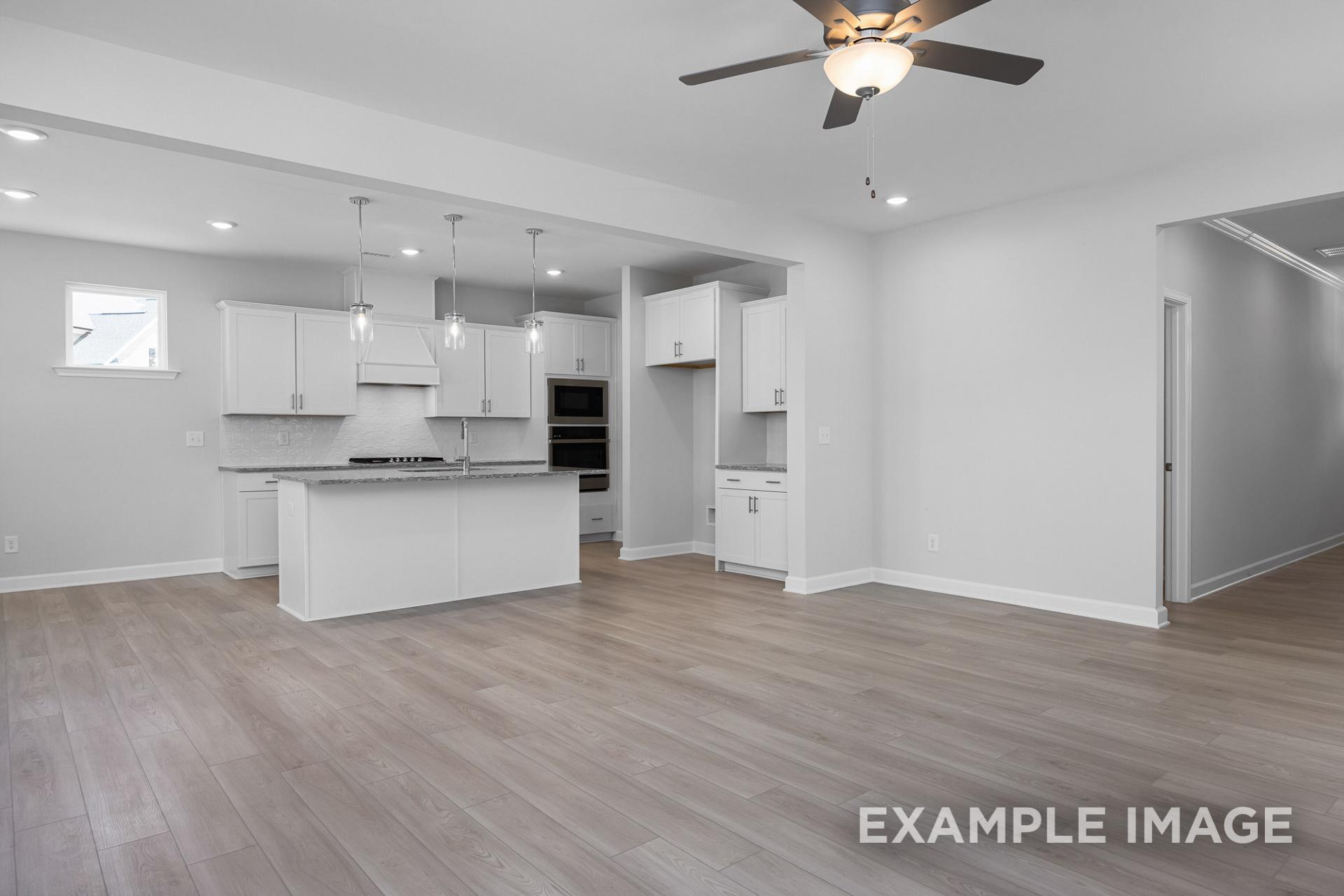 Spacious open-concept kitchen in The Gavin B by Davidson Homes with white cabinets, large island, and recessed lighting