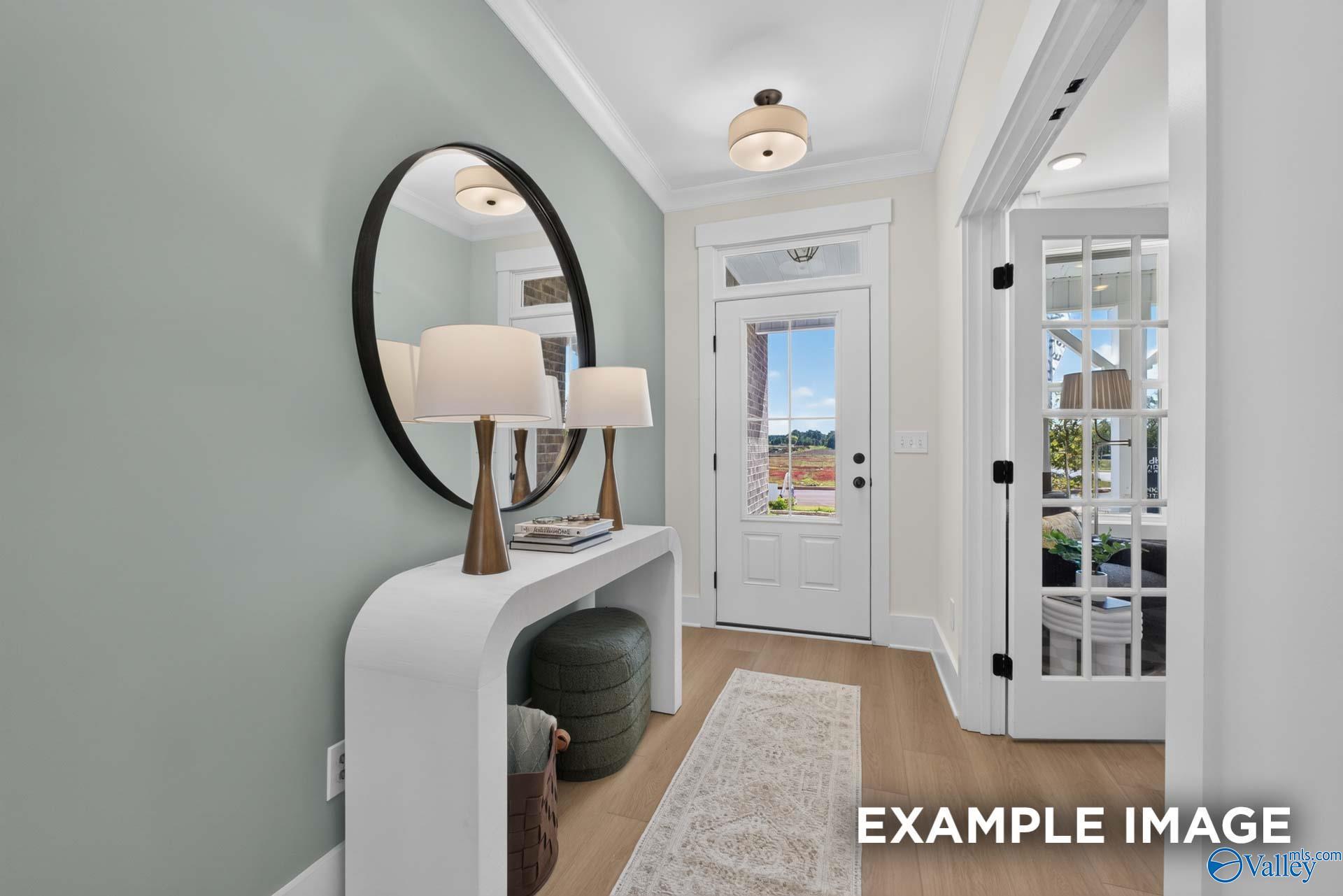 Elegant foyer with round mirror, white console table, and glass-panel front door in Davidson Homes Ashport K plan, Hazel Green AL