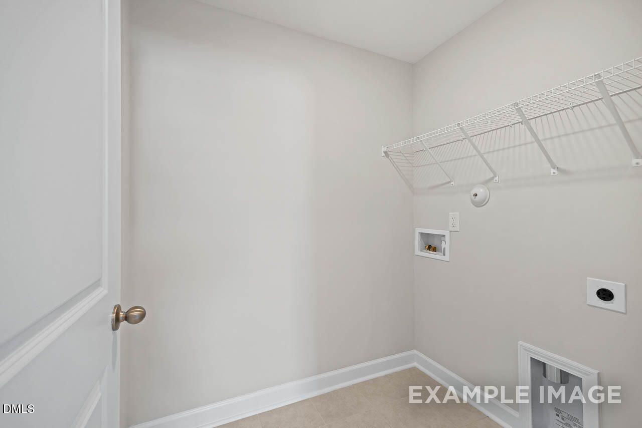 Laundry room with wire shelving and utility hookups in The Graham floor plan by Davidson Homes in Springvale, Fuquay-Varina.