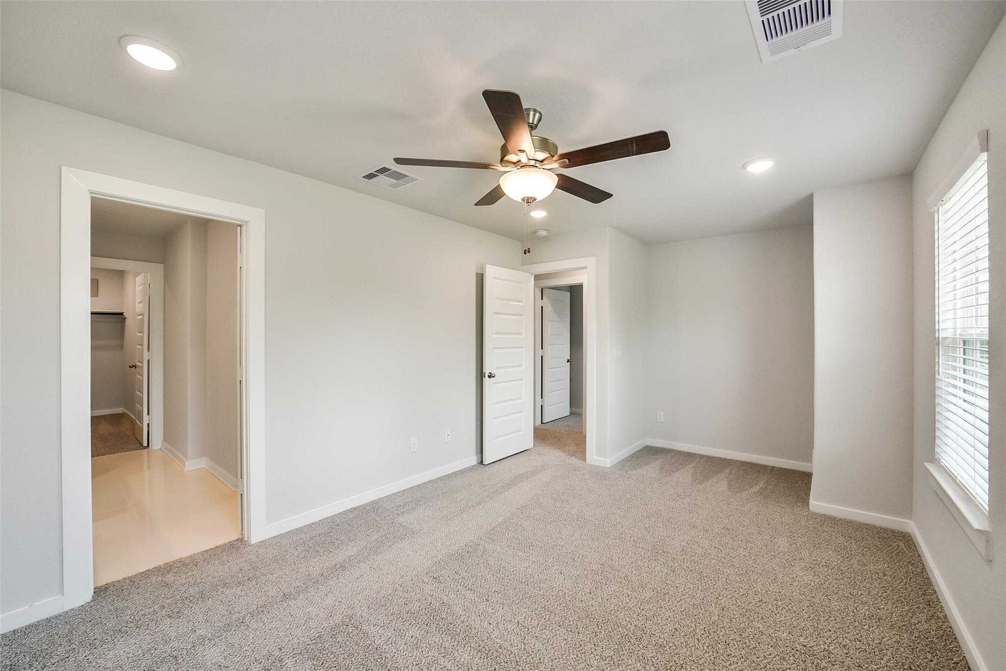 Spacious empty bedroom with ceiling fan, recessed lights, and carpet in Davidson Homes The Trinity F, Magnolia, Texas
