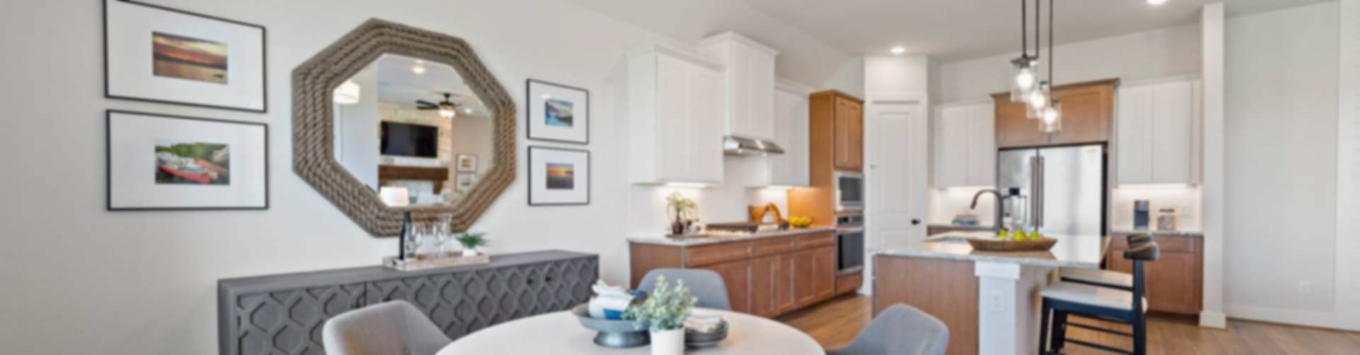 Modern dining area with white round table, gray upholstered chairs, and open kitchen in new Magnolia home
