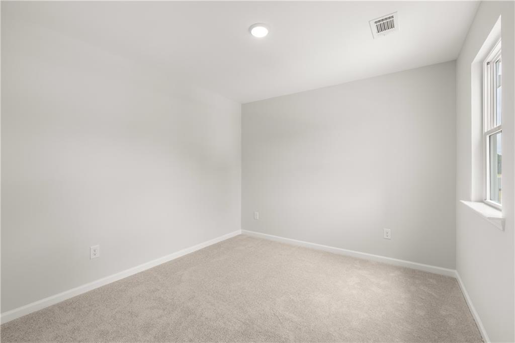 Bright, neutral guest bedroom with plush carpeting in The Sinclair B floor plan at Cedar Farms in Winder, Georgia.