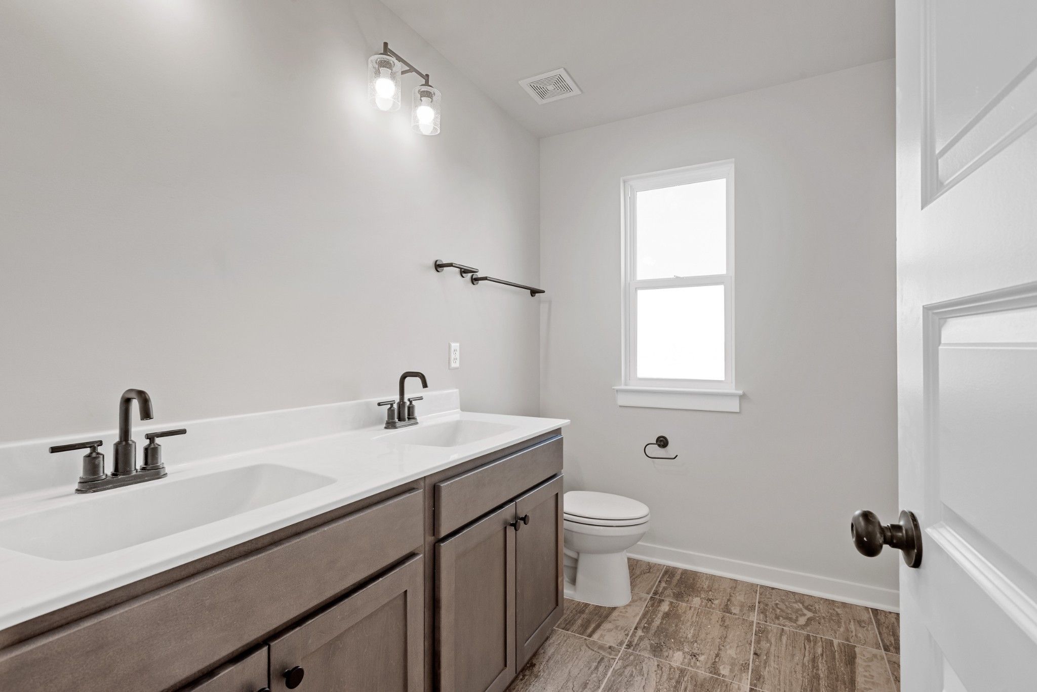 Modern double-sink vanity with shaker cabinets, white quartz tops, and wood flooring in Davidson Homes The Willow B bathroom, Calista Farms, White House, TN