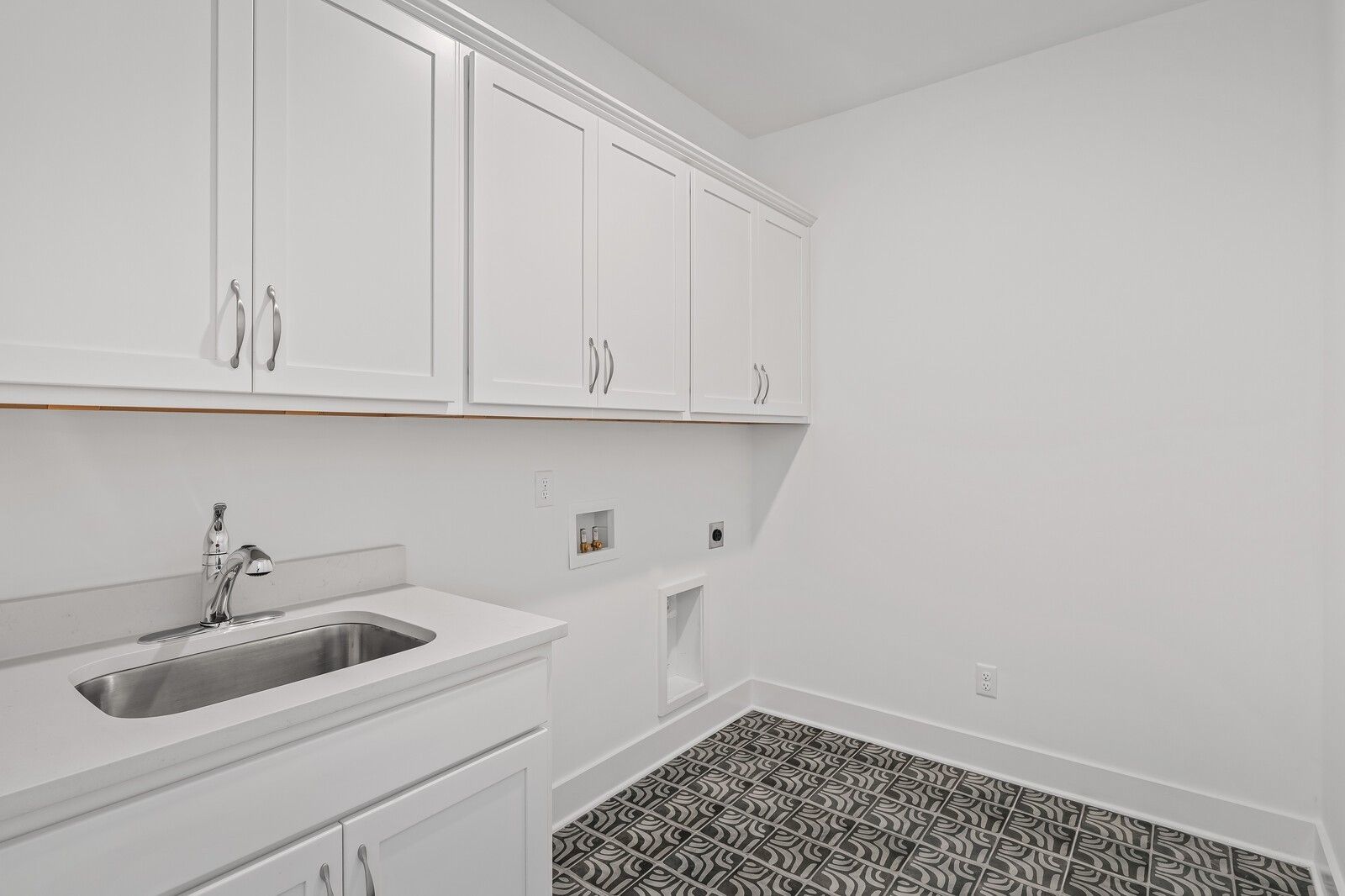 Modern laundry room with white shaker cabinets, stainless sink, and black-white patterned tile floor in Davidson Homes The Hawkins, Murfreesboro, TN