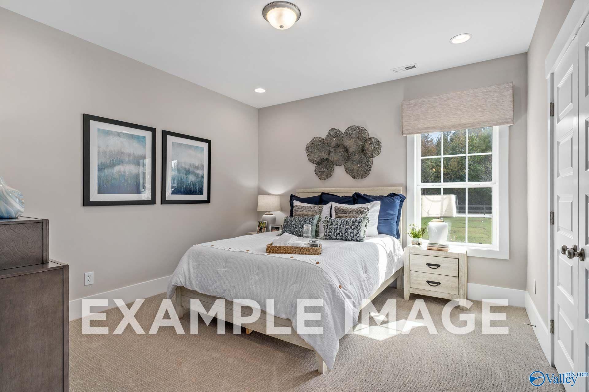 Bright guest bedroom with navy accents and white bedding in Davidson Homes' The Harrison floor plan, Hartselle, Alabama