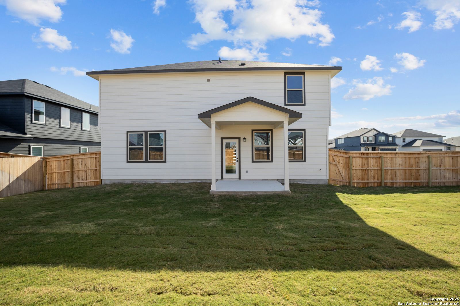 Rear view of two-story Davidson Homes The Douglas C with covered patio, fenced grassy backyard in Hannah Heights, Seguin, Texas