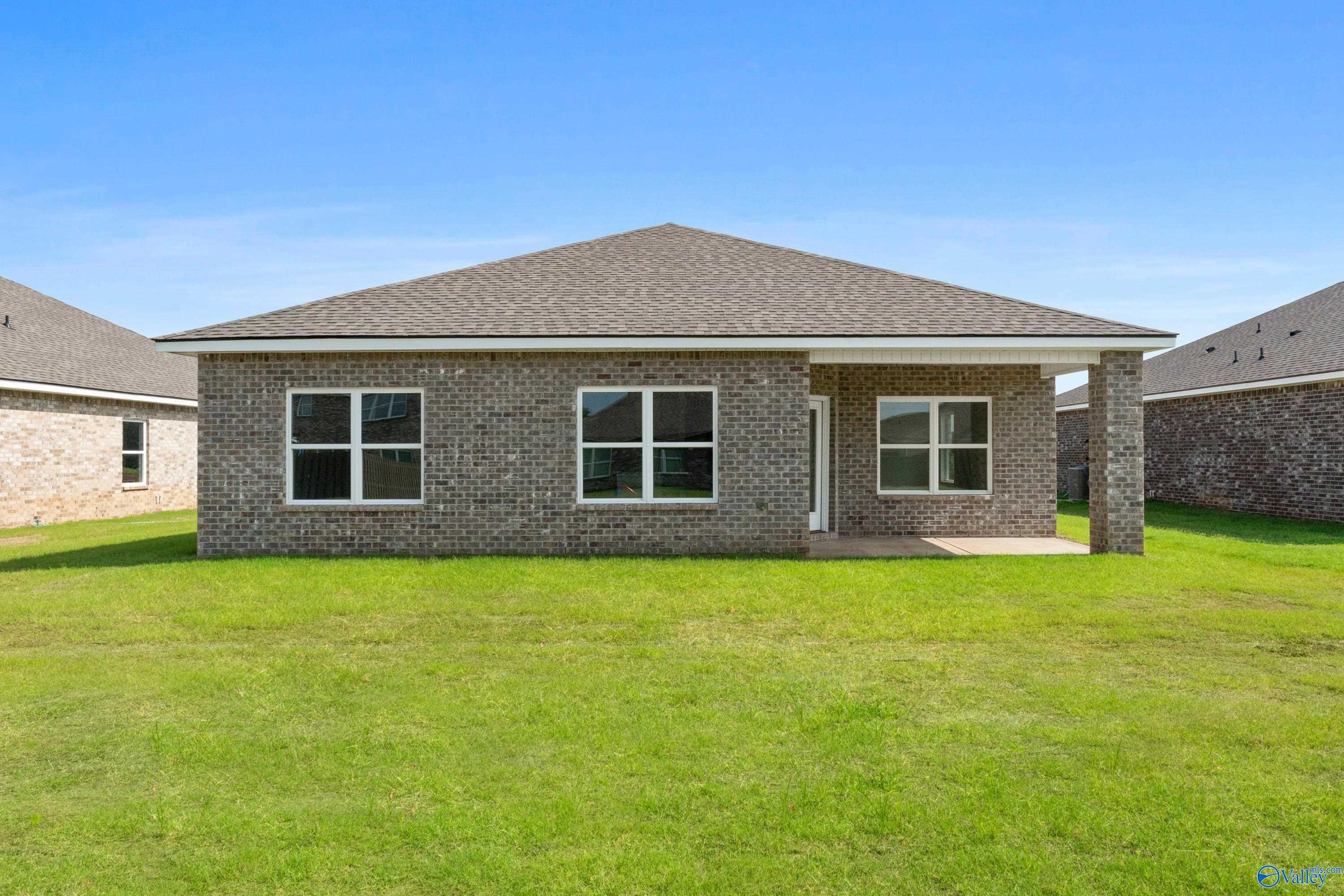 Single-story brick ranch home with gabled roof, double windows, and covered entry porch on lush green lawn in Clearview, Hazel Green, Alabama