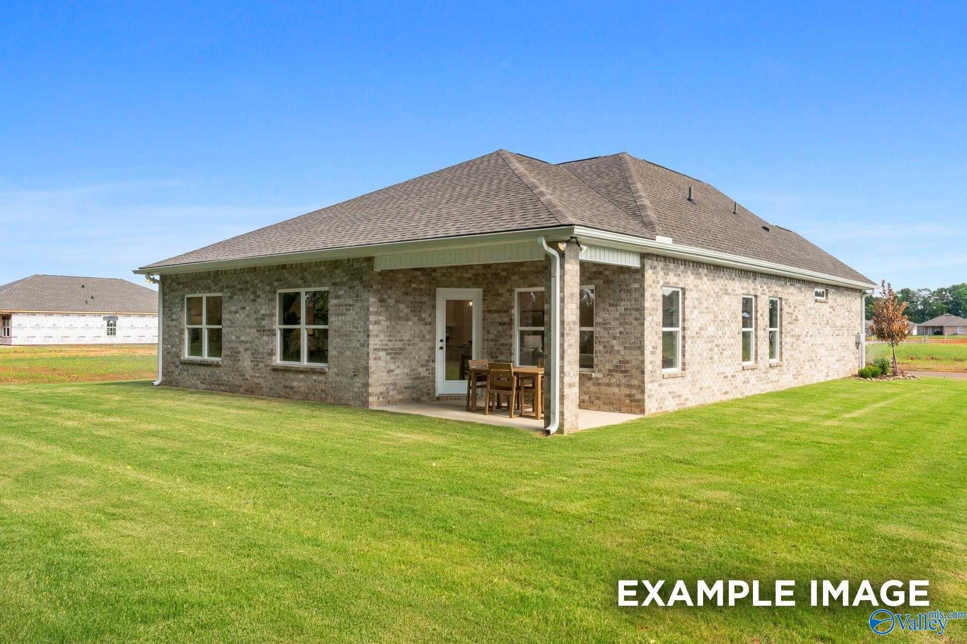 Single-story brick home with covered porch, windows, and lush green lawn in Jaguar Hills, Huntsville, Alabama