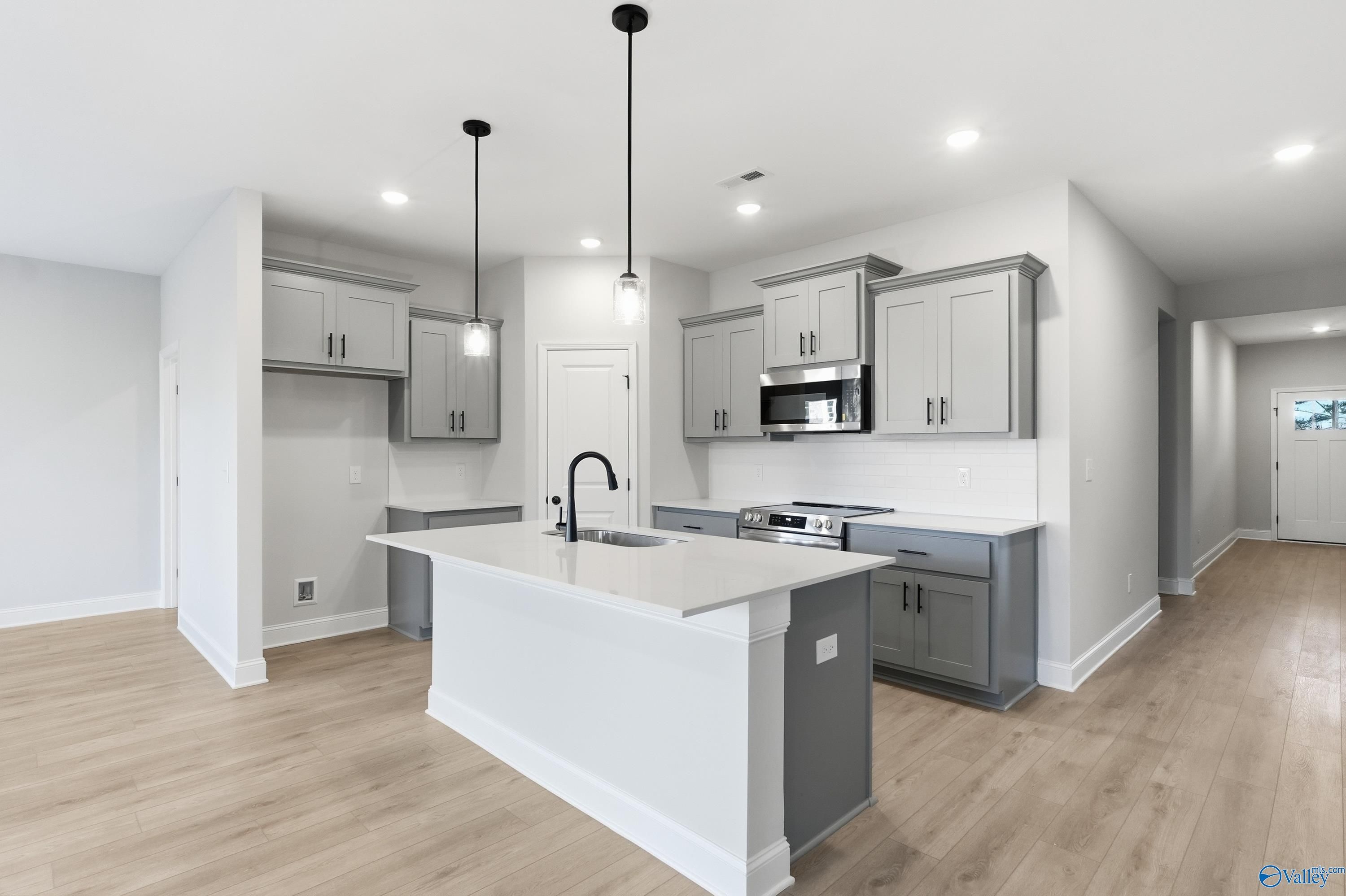 Modern kitchen with gray shaker cabinets, white quartz island sink, stainless appliances in Davidson Homes The Daphne C, Athens AL