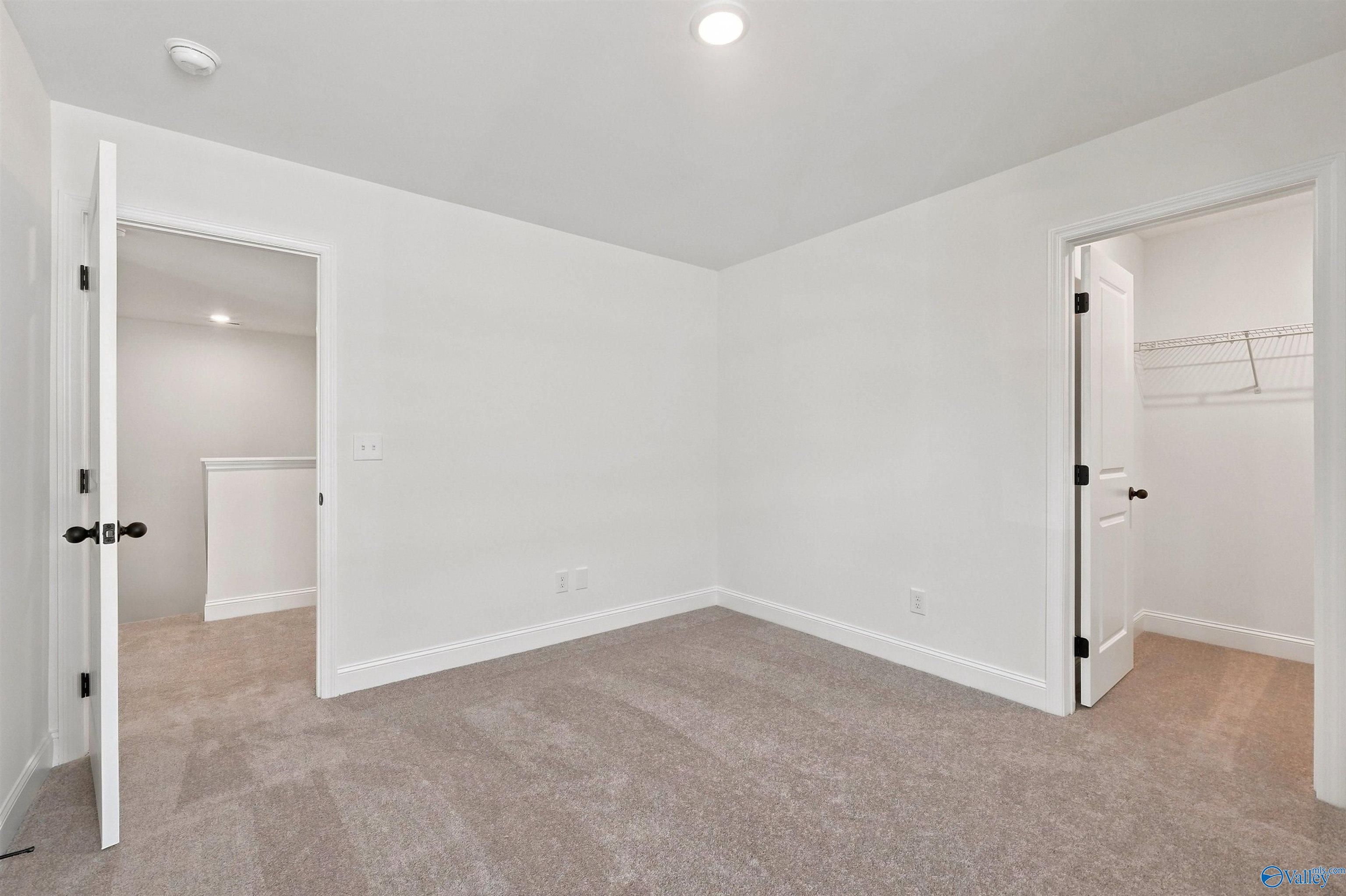 Spacious carpeted bedroom with walk-in closet in The Chelsea C floor plan by Davidson Homes in Creek Grove, New Market.