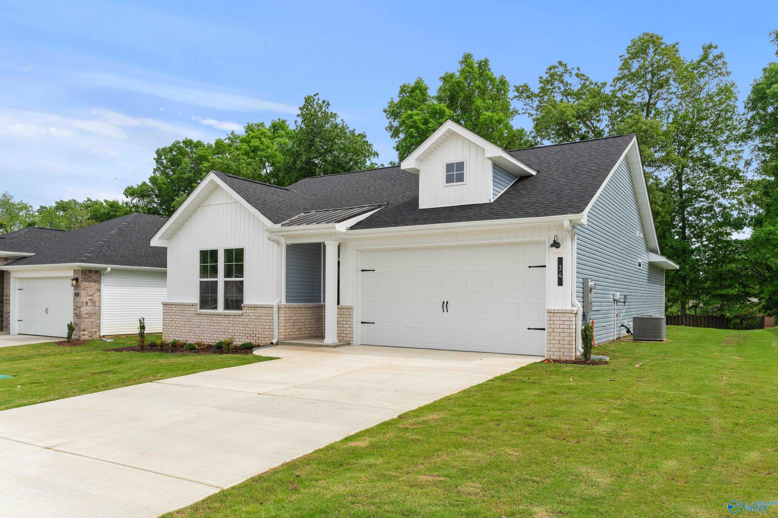 Single-story 3-bedroom home exterior with 2-car garage, white siding, brick accents, driveway, and lush green lawn in Bailey Park, Fayetteville, Tennessee by Davidson Homes The Phoenix