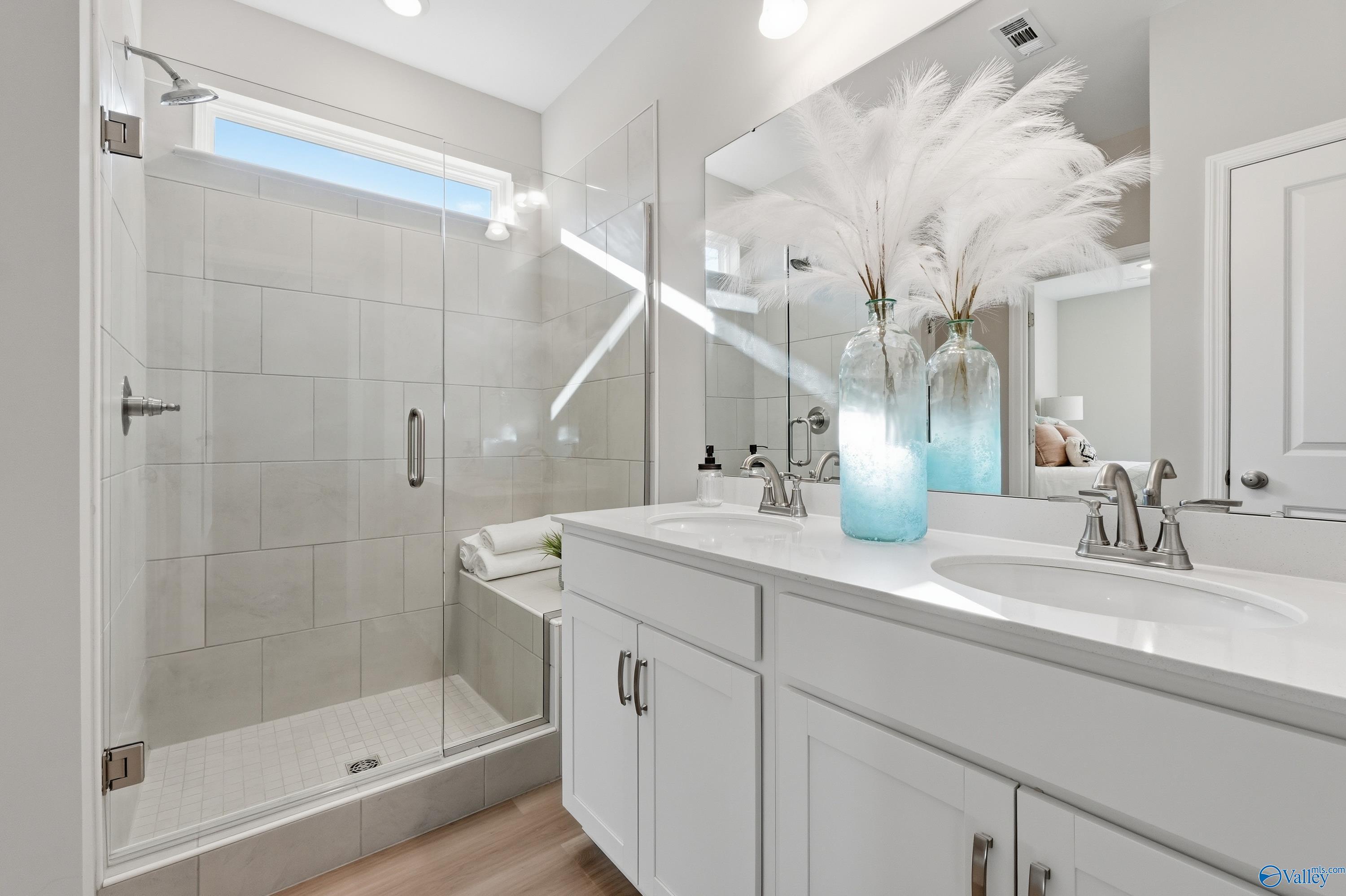 Elegant master bathroom with tiled walk-in shower, double white vanity, and blue feather vases in Davidson Homes The Polaris, Fayetteville, TN