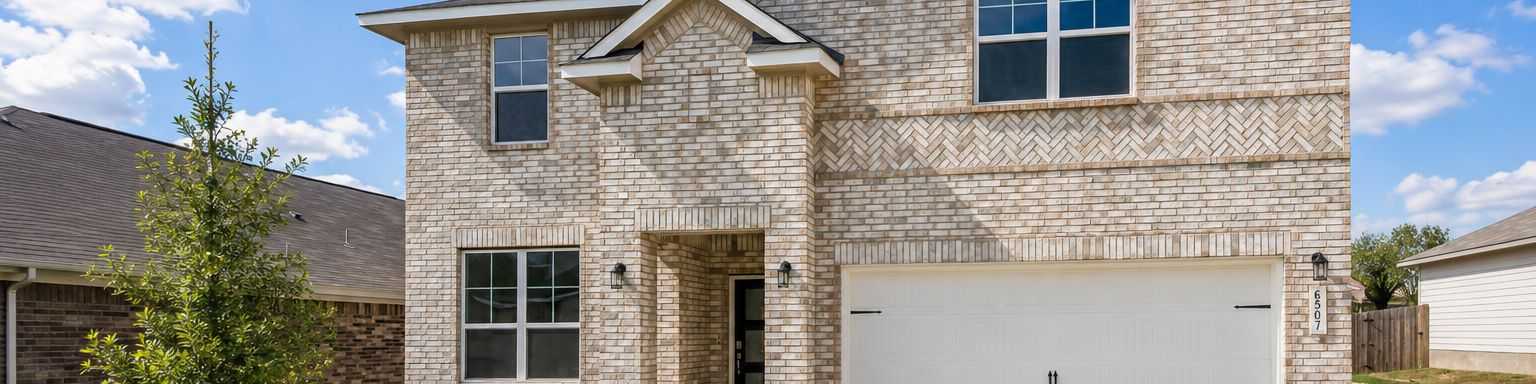 Two-story brick exterior of a Davidson Homes house at Morgan Meadows in San Antonio, Texas with a two-car garage.