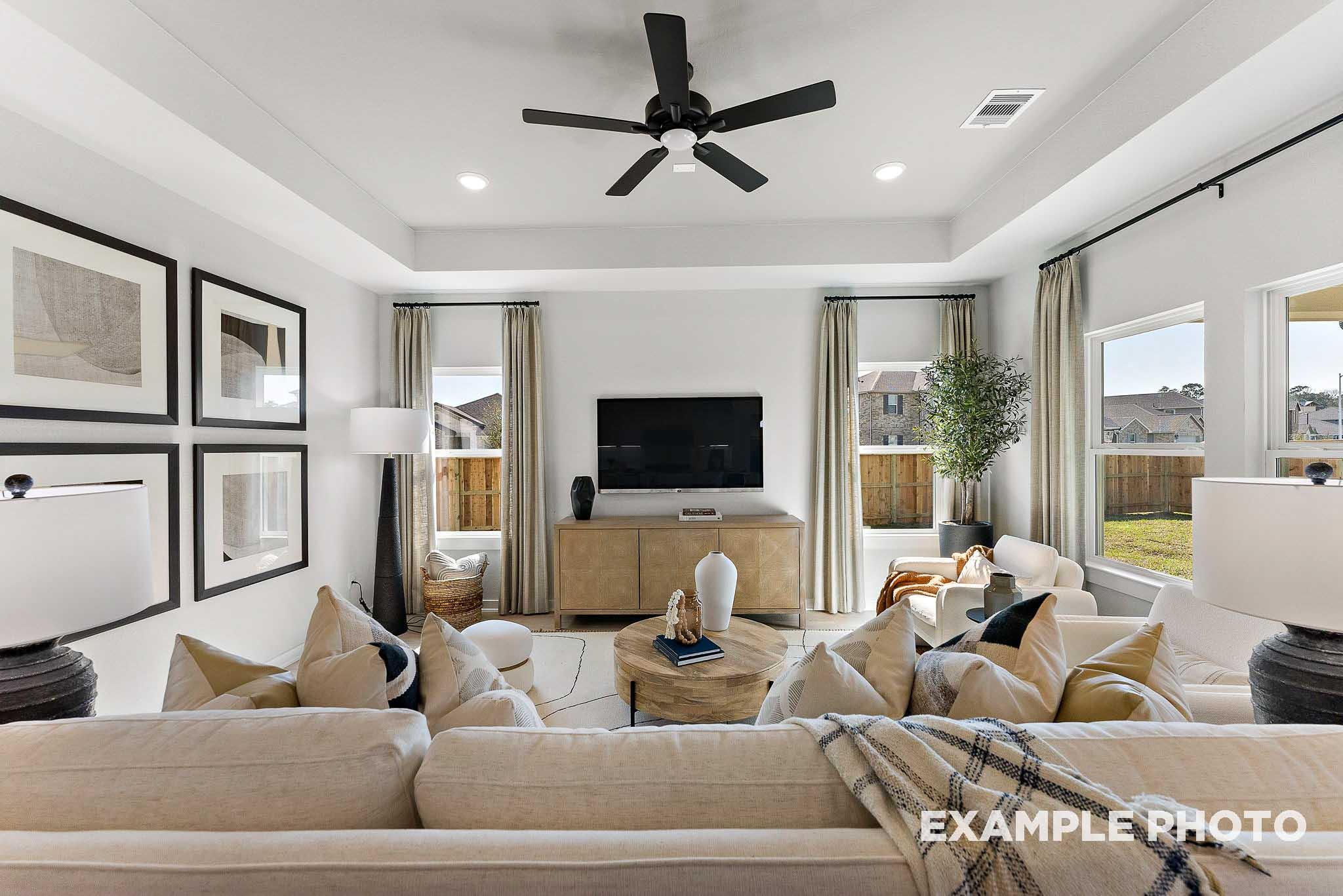 Bright, open-concept living room with tray ceiling in The Everett E floor plan at Sundance Cove in Crosby, Texas.