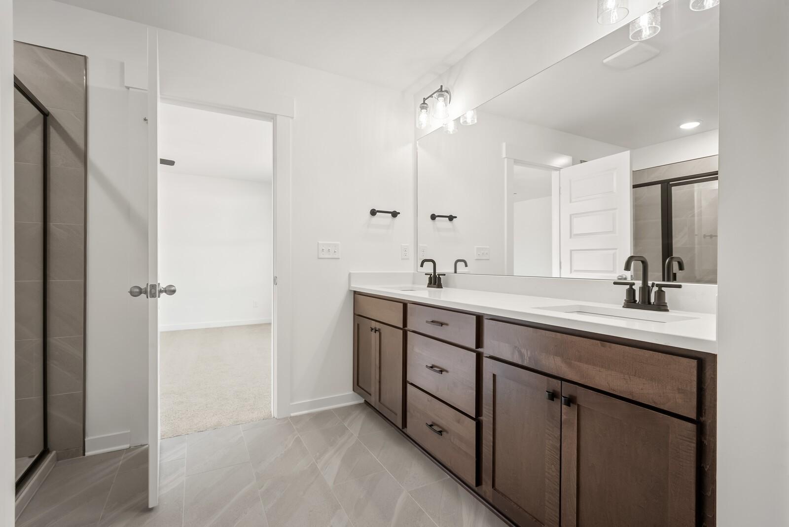 Modern master bathroom with double vanity, quartz countertop, and frameless shower in Davidson Homes The Logan C, Gallatin, TN