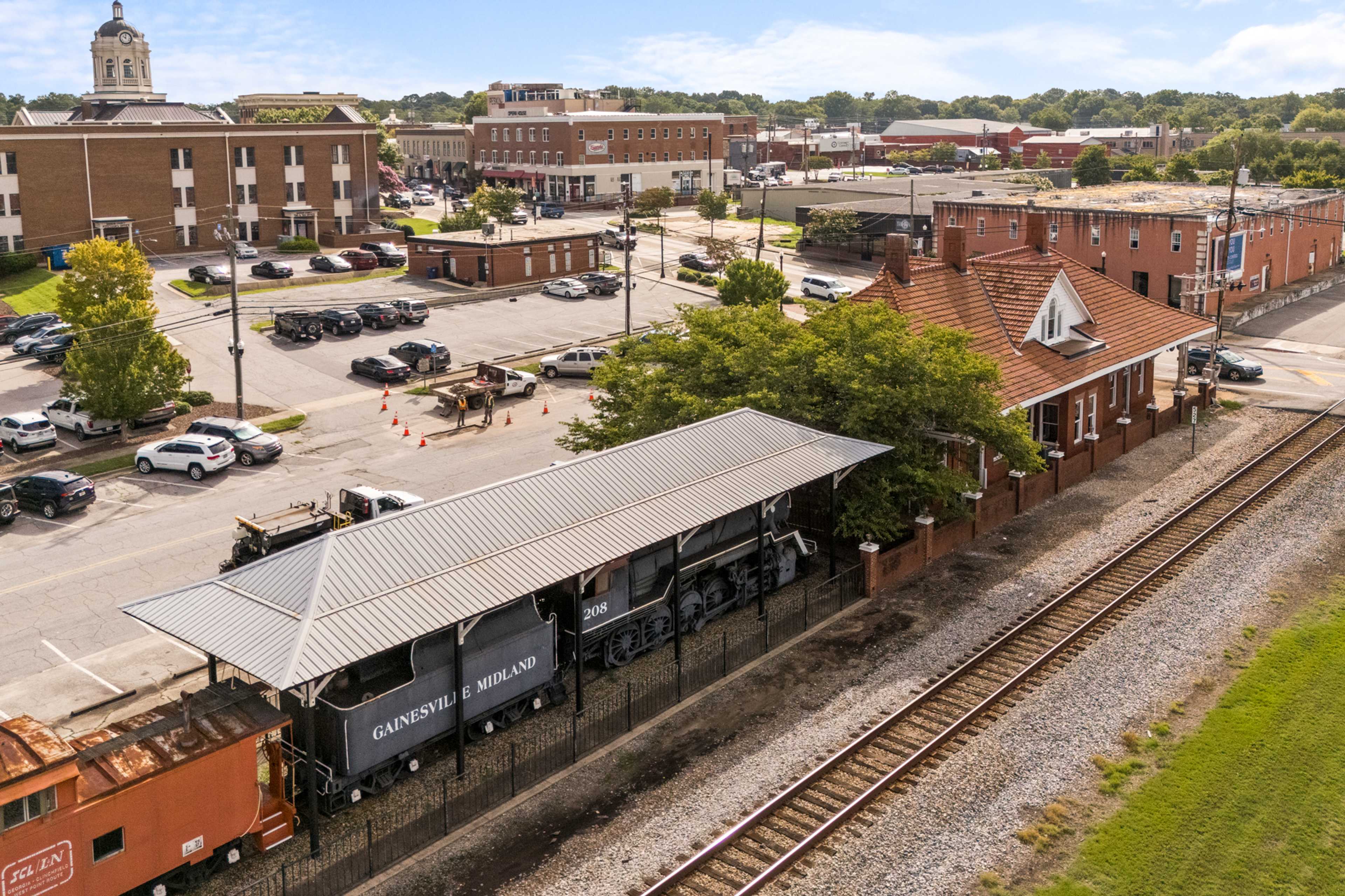 Aerial view of historic Winder Georgia downtown with brick buildings, train station, and Davidson locomotive along railroad tracks
