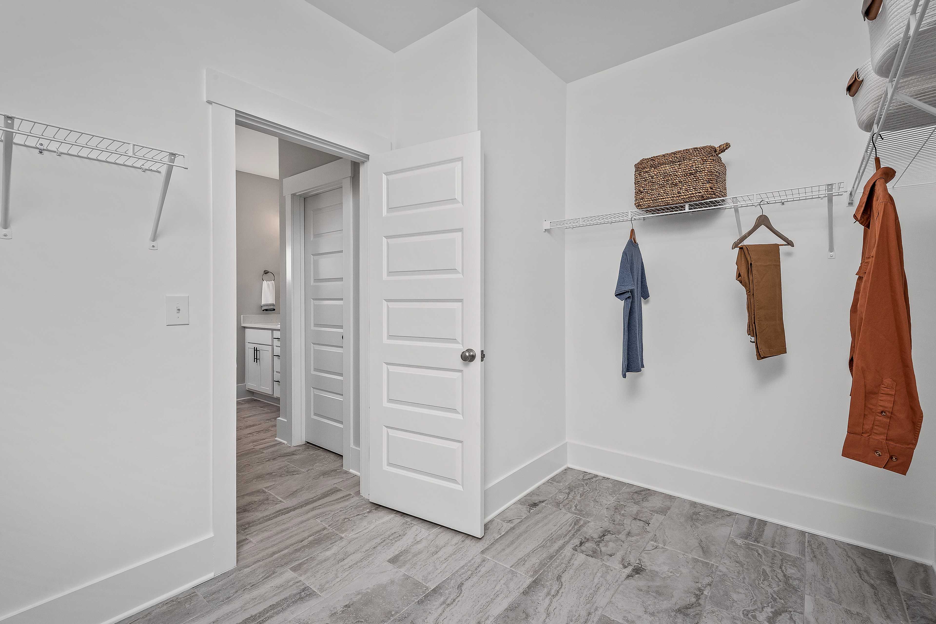 Spacious walk-in closet at Cain Park in Hartselle, Alabama by Davidson Homes with wire shelving, hanging storage and hardwood floors