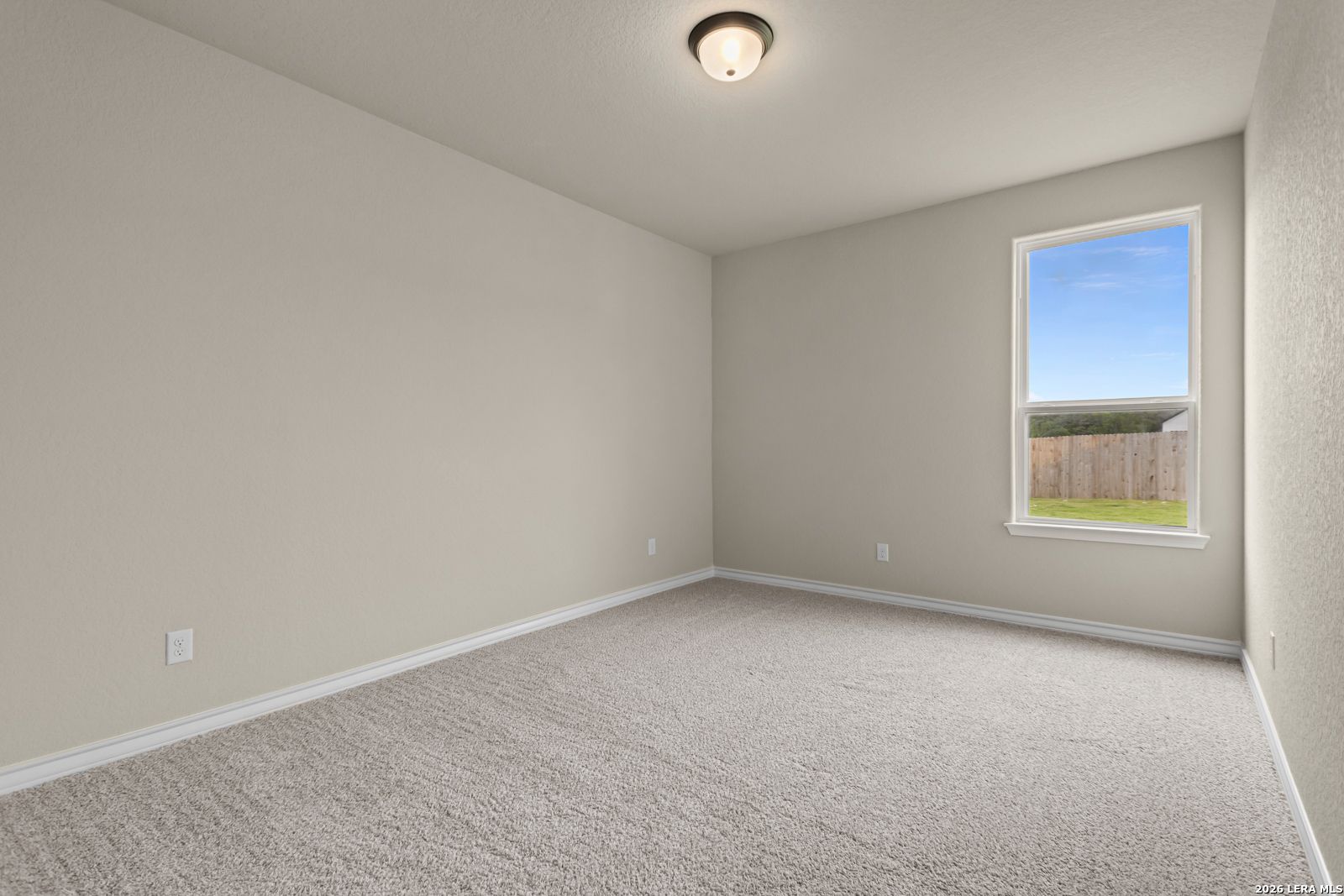 Spacious neutral-toned bedroom with plush carpeting in The Danbury H model home at The Reserve at Potranco Oaks, Texas.
