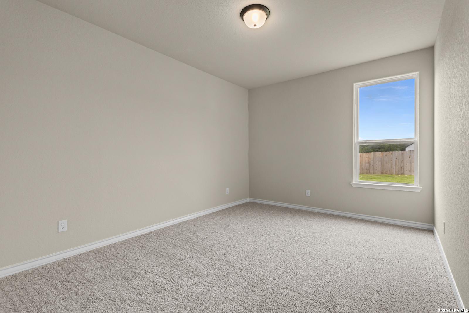 Spacious neutral-toned bedroom with plush carpeting in The Danbury H model home at The Reserve at Potranco Oaks, Texas.