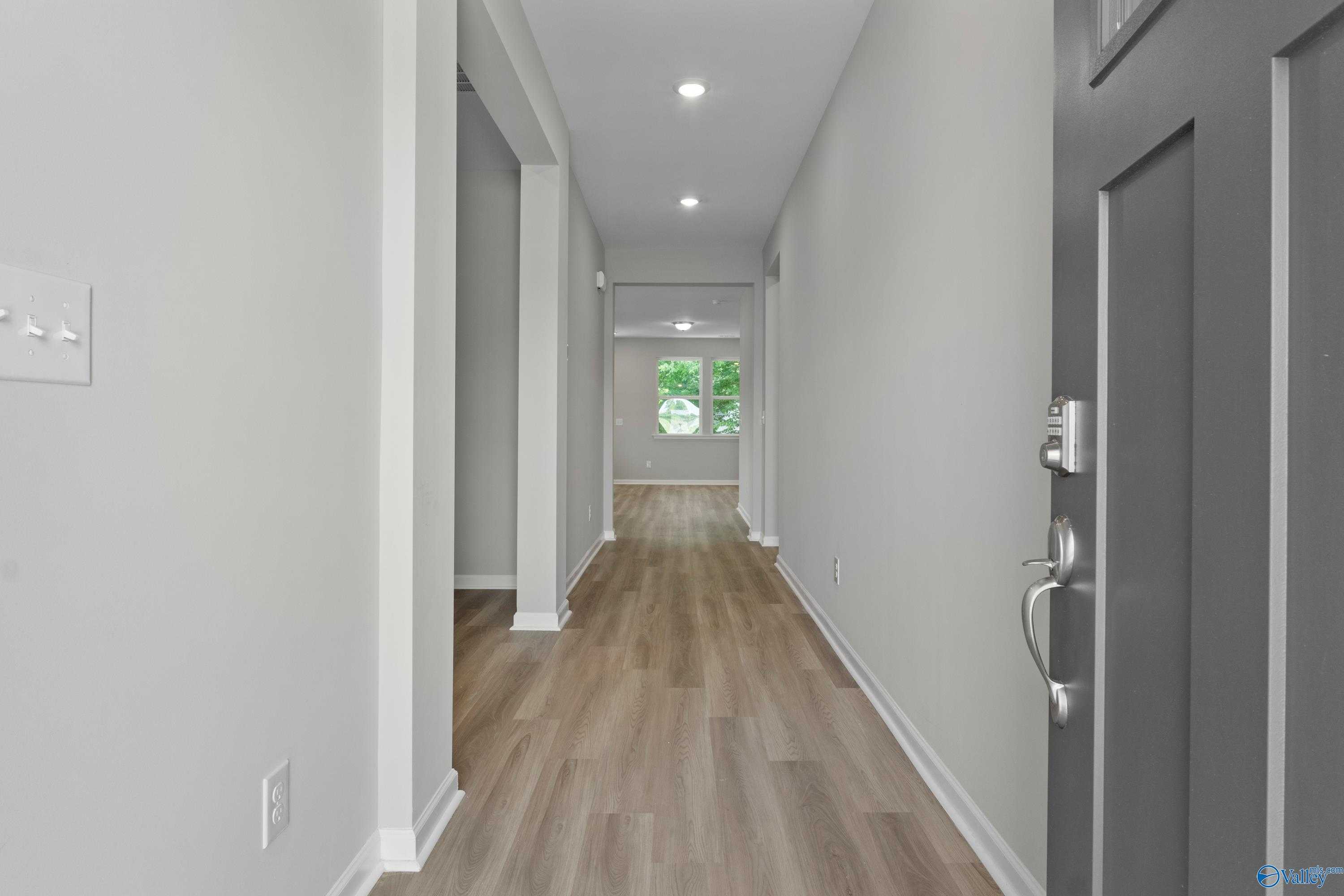 Welcoming hallway with gray walls, luxury vinyl plank flooring, and natural light in The Polaris 3-bedroom home, Fayetteville, Tennessee