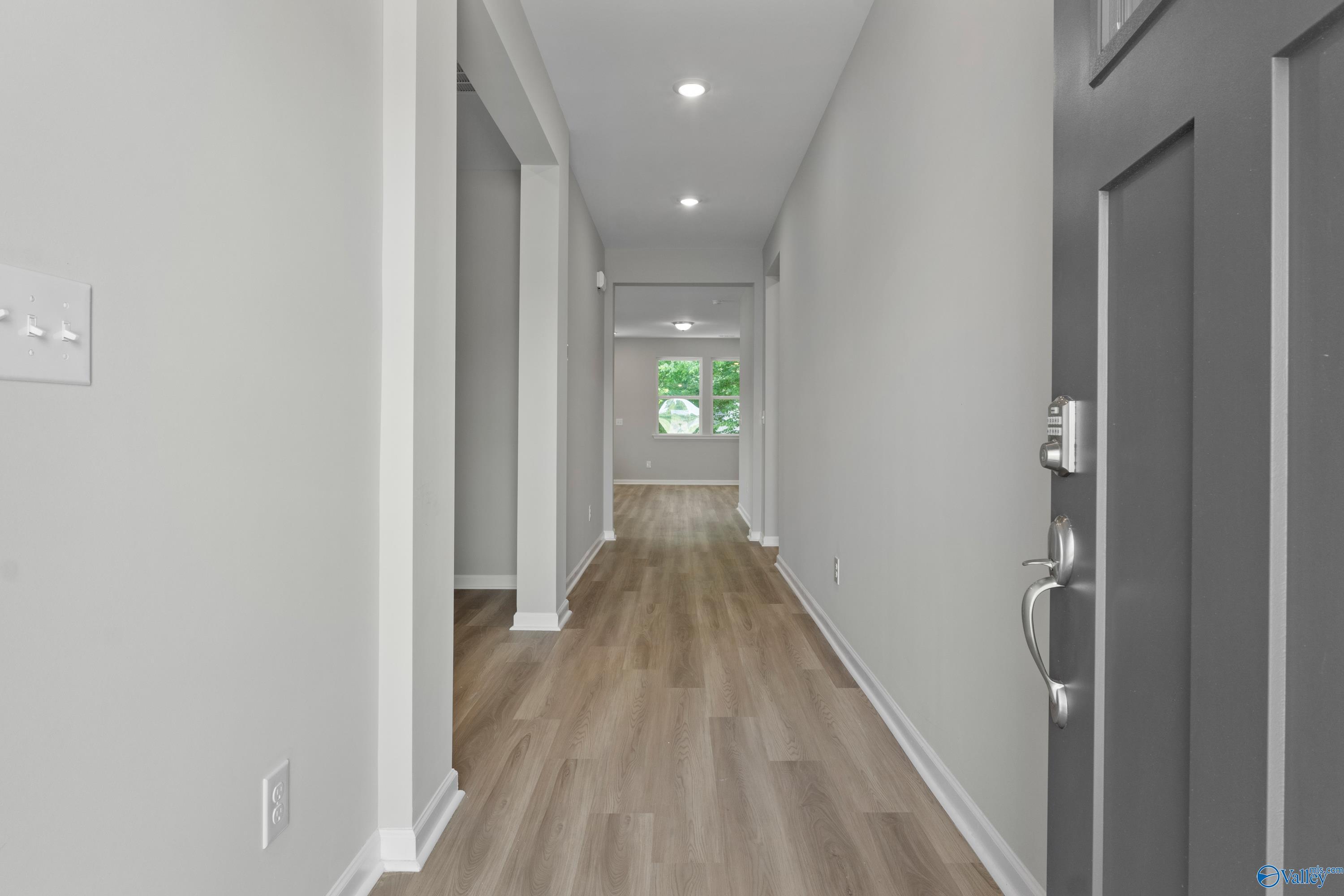 Bright hallway with light gray walls, luxury vinyl plank floors, and front door in Davidson Homes The Polaris, Bailey Park, Fayetteville TN