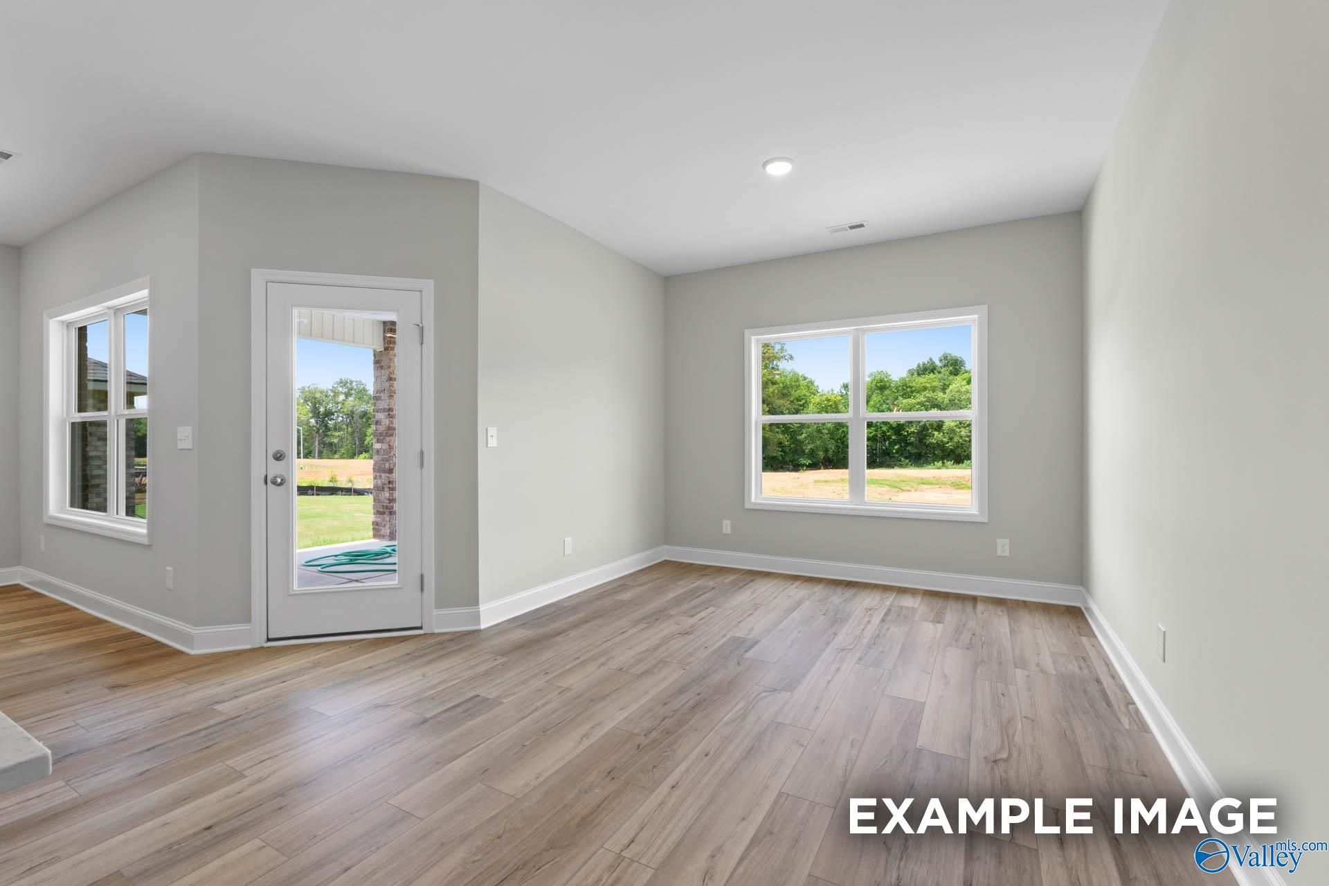 Spacious living room with hardwood floors, gray walls, French doors to lush backyard in Davidson Homes The Everett, Meridianville, Alabama