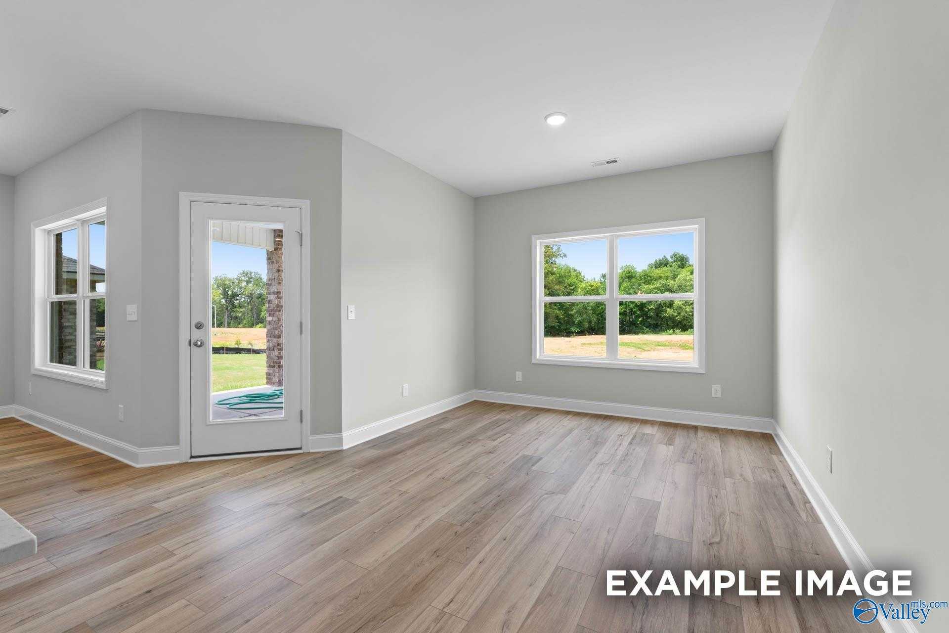 Spacious living room with hardwood floors, gray walls, French doors to lush backyard in Davidson Homes The Everett, Meridianville, Alabama