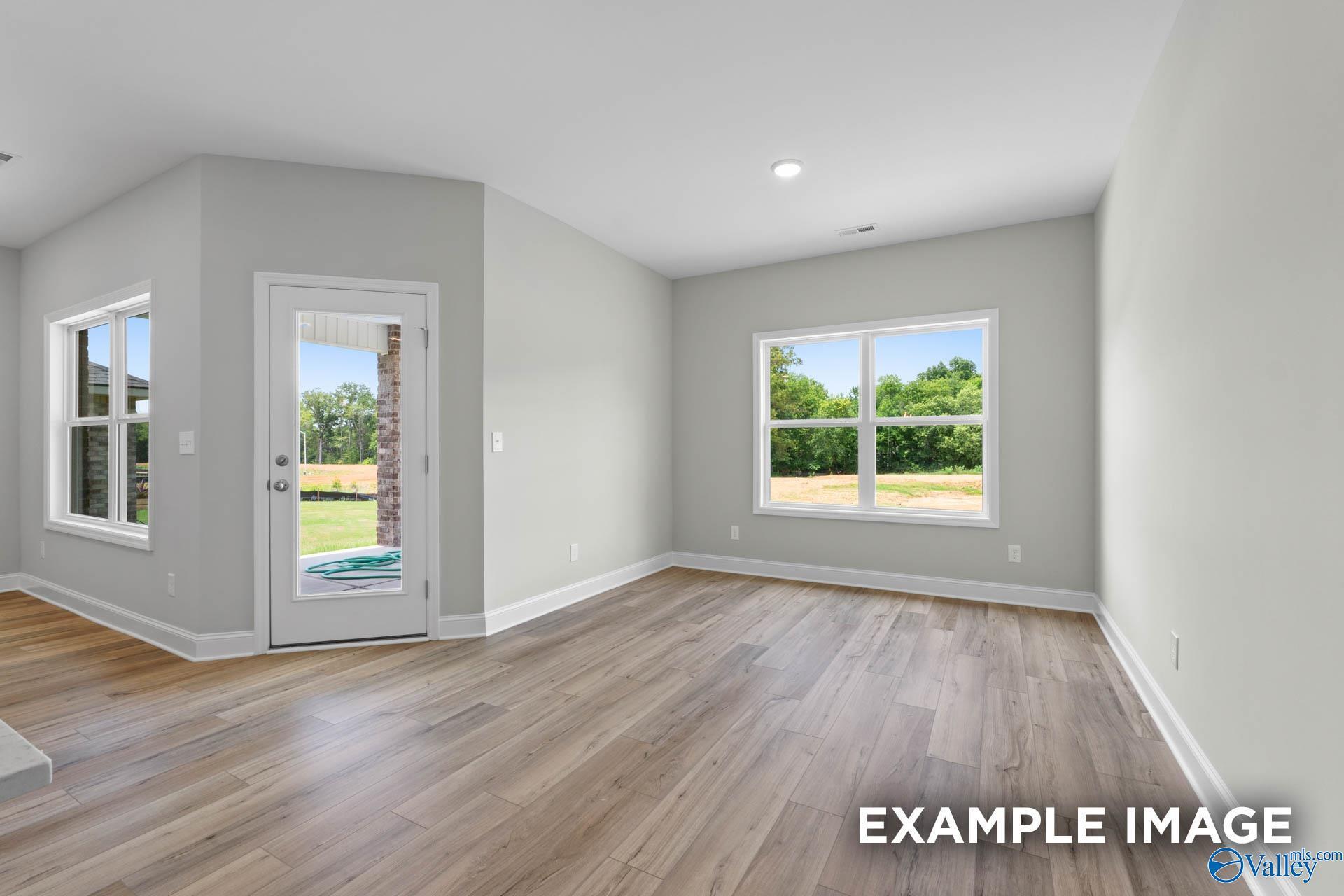 Spacious living room with hardwood floors, gray walls, and French doors to lush backyard in Davidson Homes The Everett B, Athens, AL