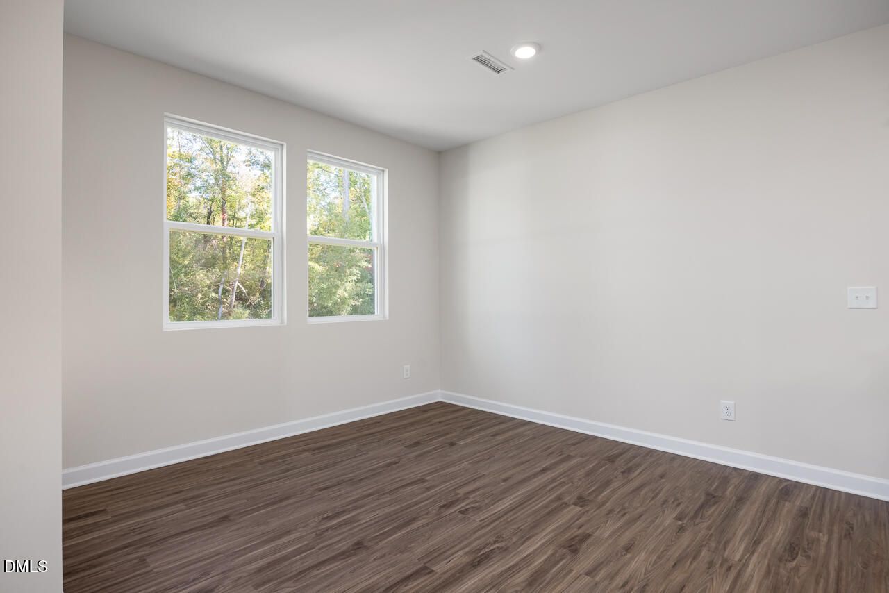 Sunlit secondary bedroom with large windows, neutral walls, and hardwood floors in Davidson Homes The Grace C, Lillington NC
