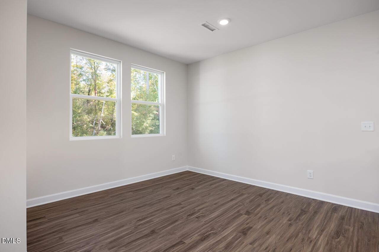 Sunlit secondary bedroom with large windows, neutral walls, and hardwood floors in Davidson Homes The Grace C, Lillington NC