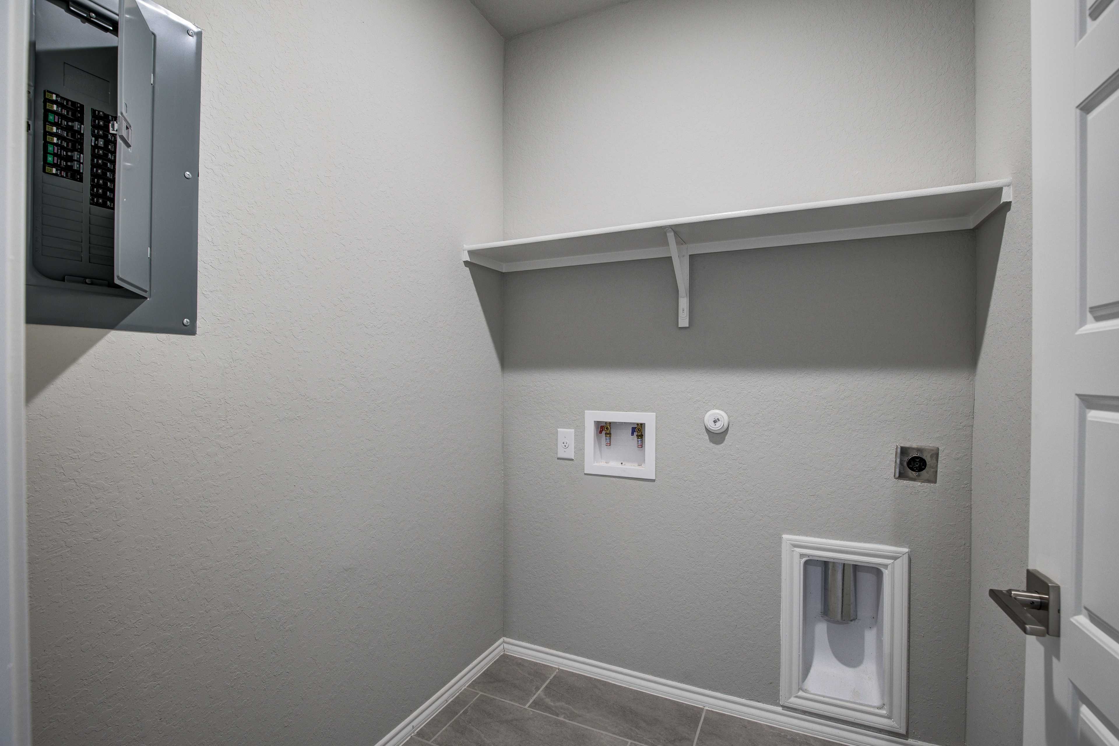 The Asheville laundry room featuring gray walls, electrical panel, built-in shelf, dryer vent, and utility outlets