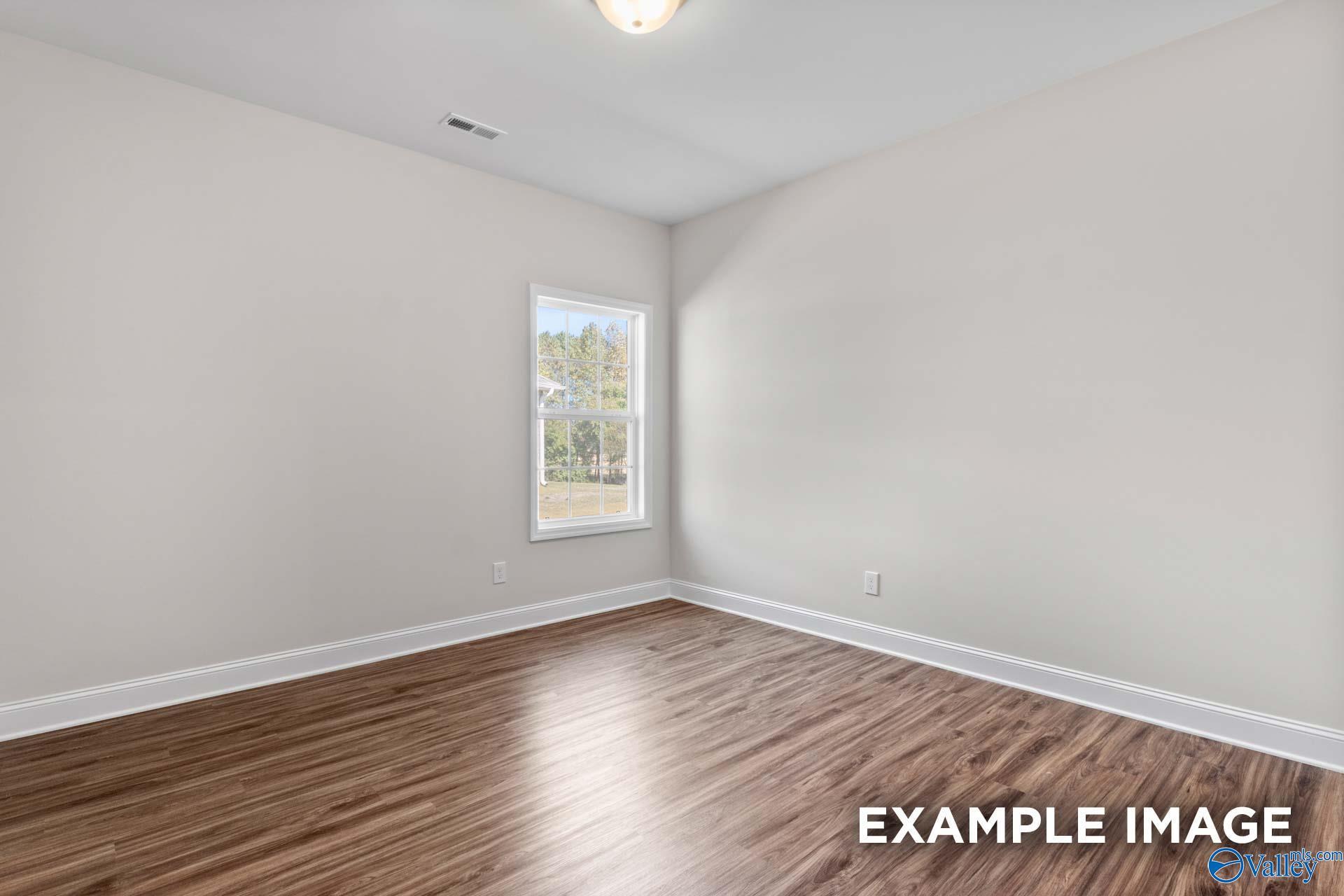 Bright secondary bedroom with hardwood floors, large window, and neutral walls in Davidson Homes Montgomery C, Harvest AL