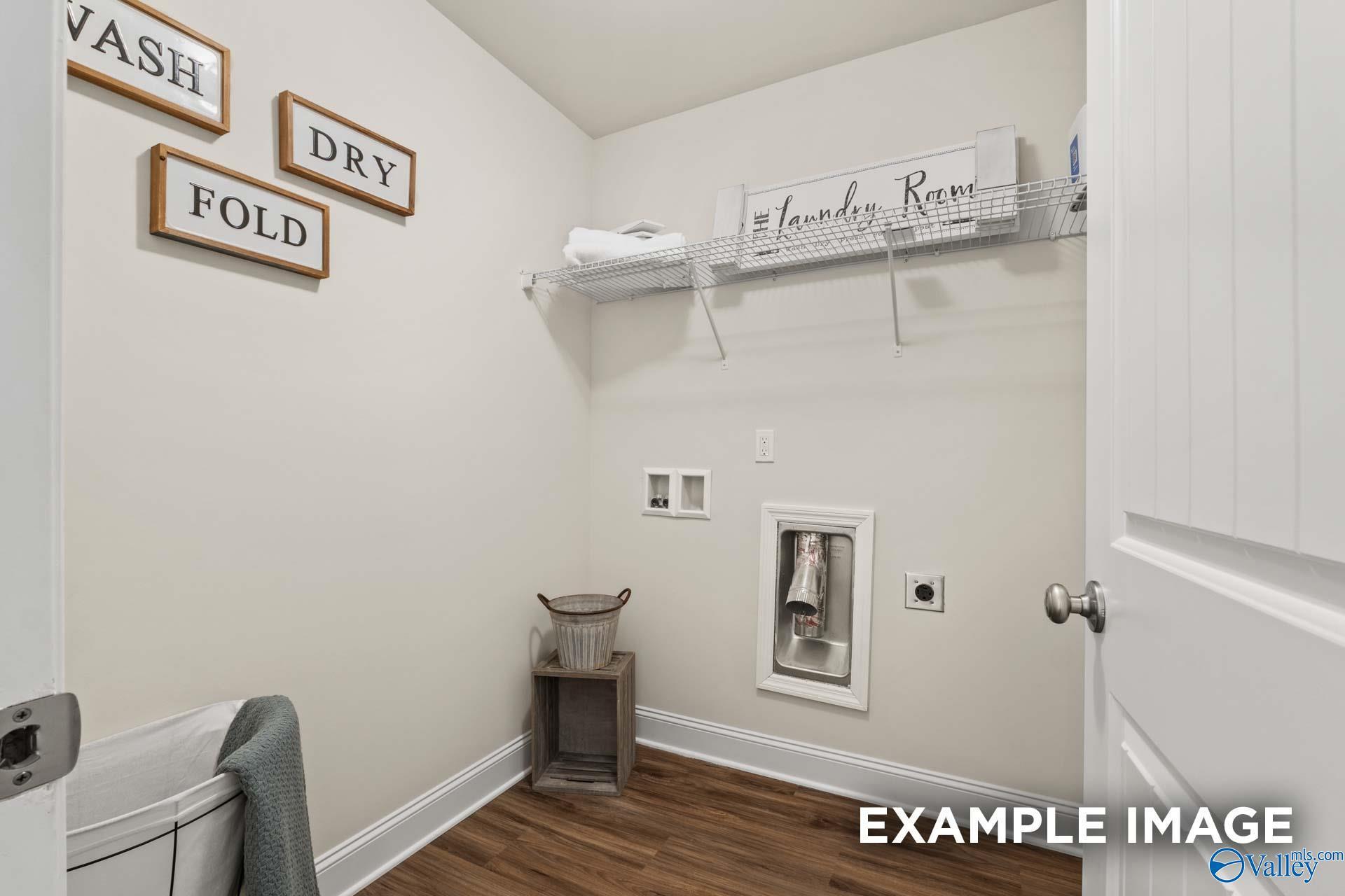 Cozy laundry room featuring wooden "Wash Dry Fold" signs, washer-dryer area, and utility sink in Davidson Homes The Franklin C, New Market, Alabama