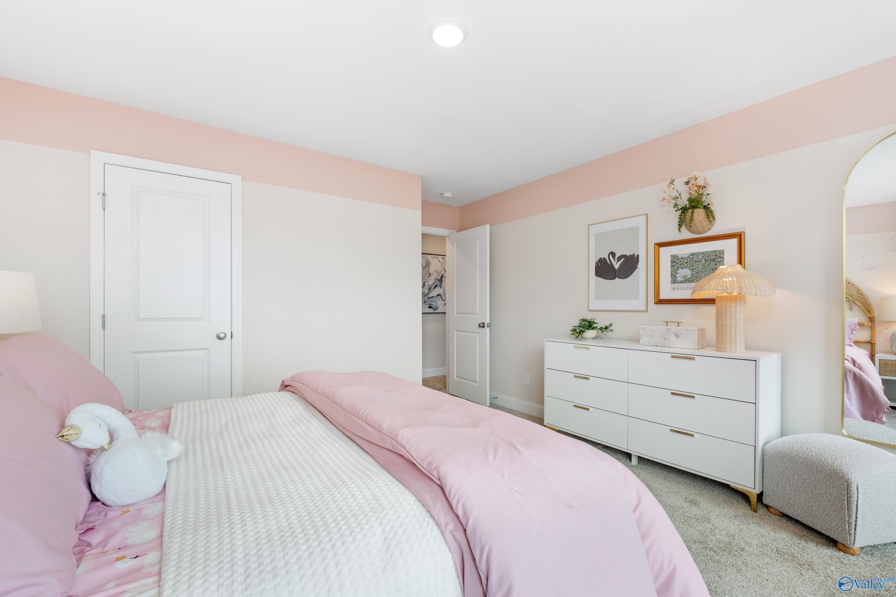 Cozy pink bedroom with plush white swan teddy, tufted bed, white dresser, arched mirror in Davidson Homes The Camden, Huntsville AL