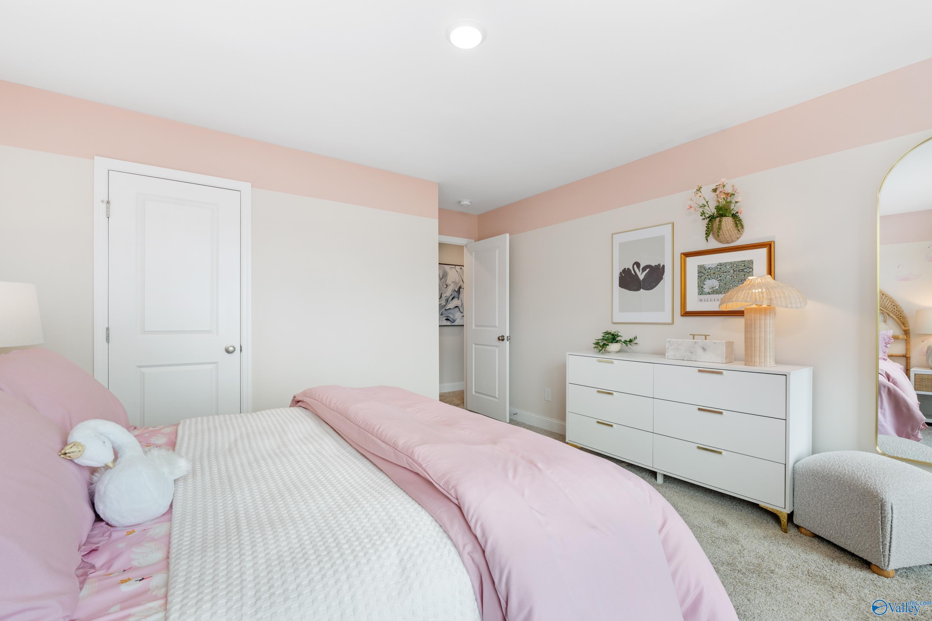 Cozy pink bedroom with plush white swan teddy, tufted bed, white dresser, arched mirror in Davidson Homes The Camden, Huntsville AL