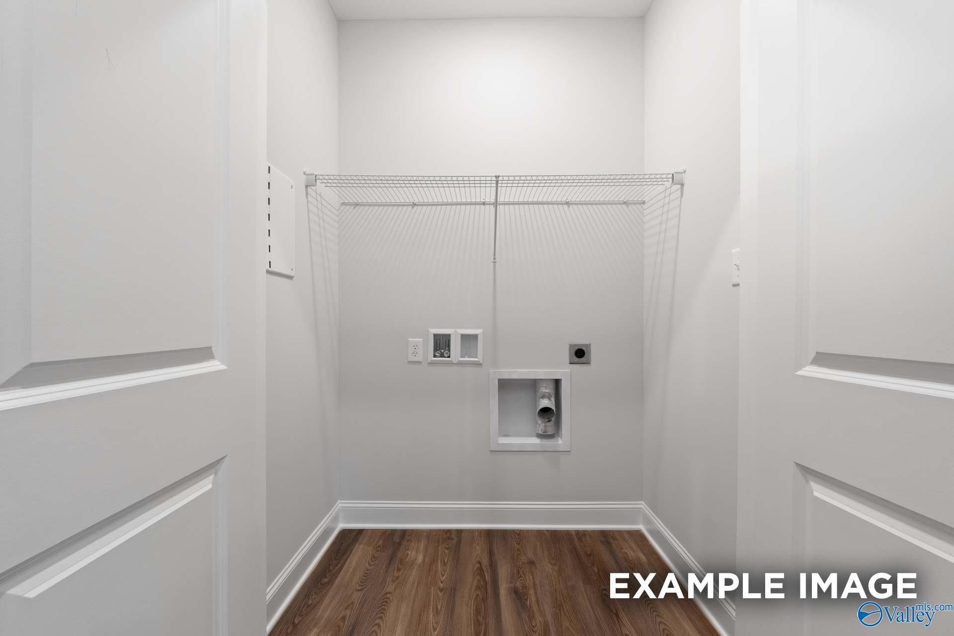 Bright laundry room with washer/dryer hookups, hanging rod, and hardwood floors in Davidson Homes The Cumberland, Decatur Alabama