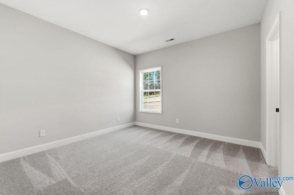 Bright secondary bedroom featuring gray walls, large window, and plush carpet in Davidson Homes The Montgomery B, Hartselle, Alabama
