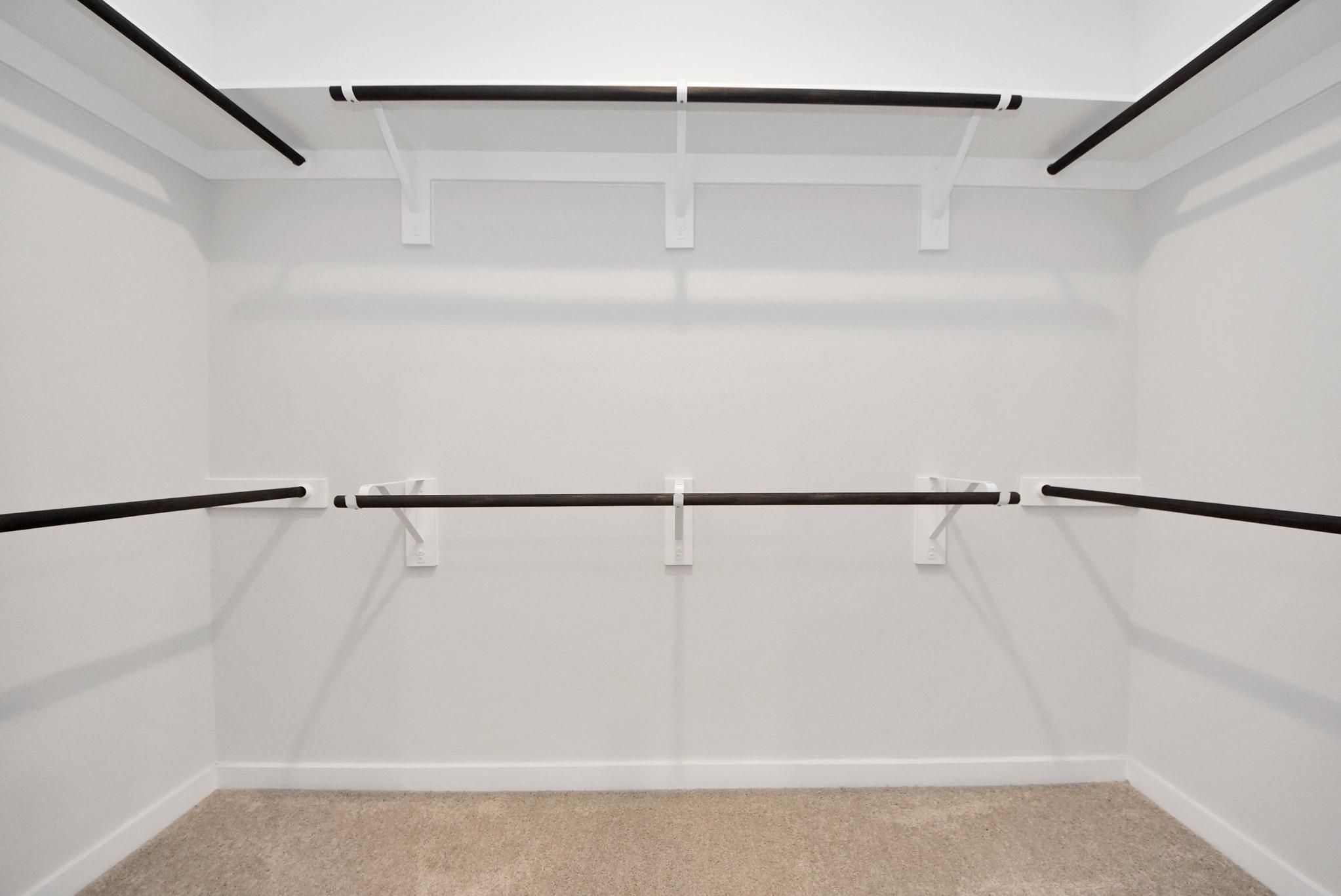 Spacious walk-in closet with double-tier shelving in The Daphne F floor plan at Sundance Cove in Crosby, Texas.