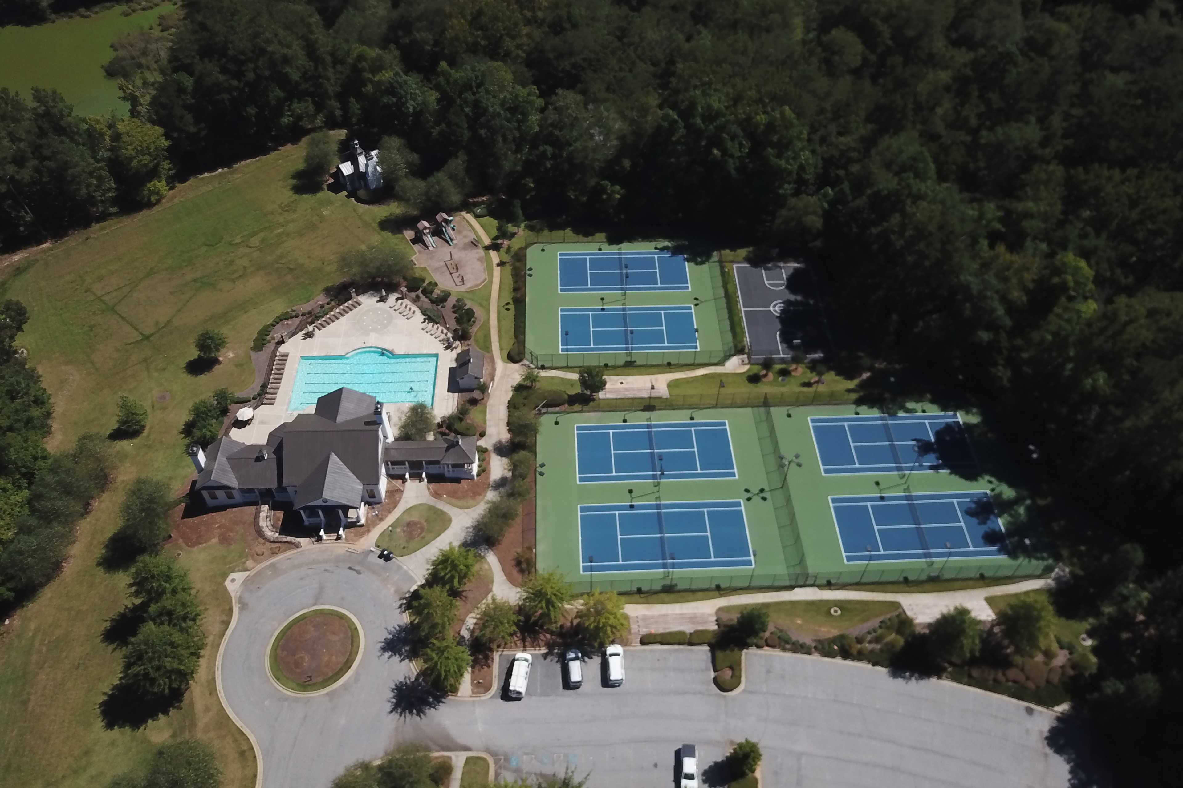 Aerial view of resort-style pool, multiple tennis courts and clubhouse at Riverwood in Dallas, Georgia